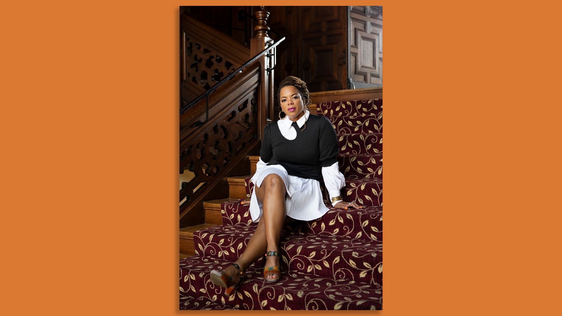 Airea Matthews sits on red-carpeted stairs.