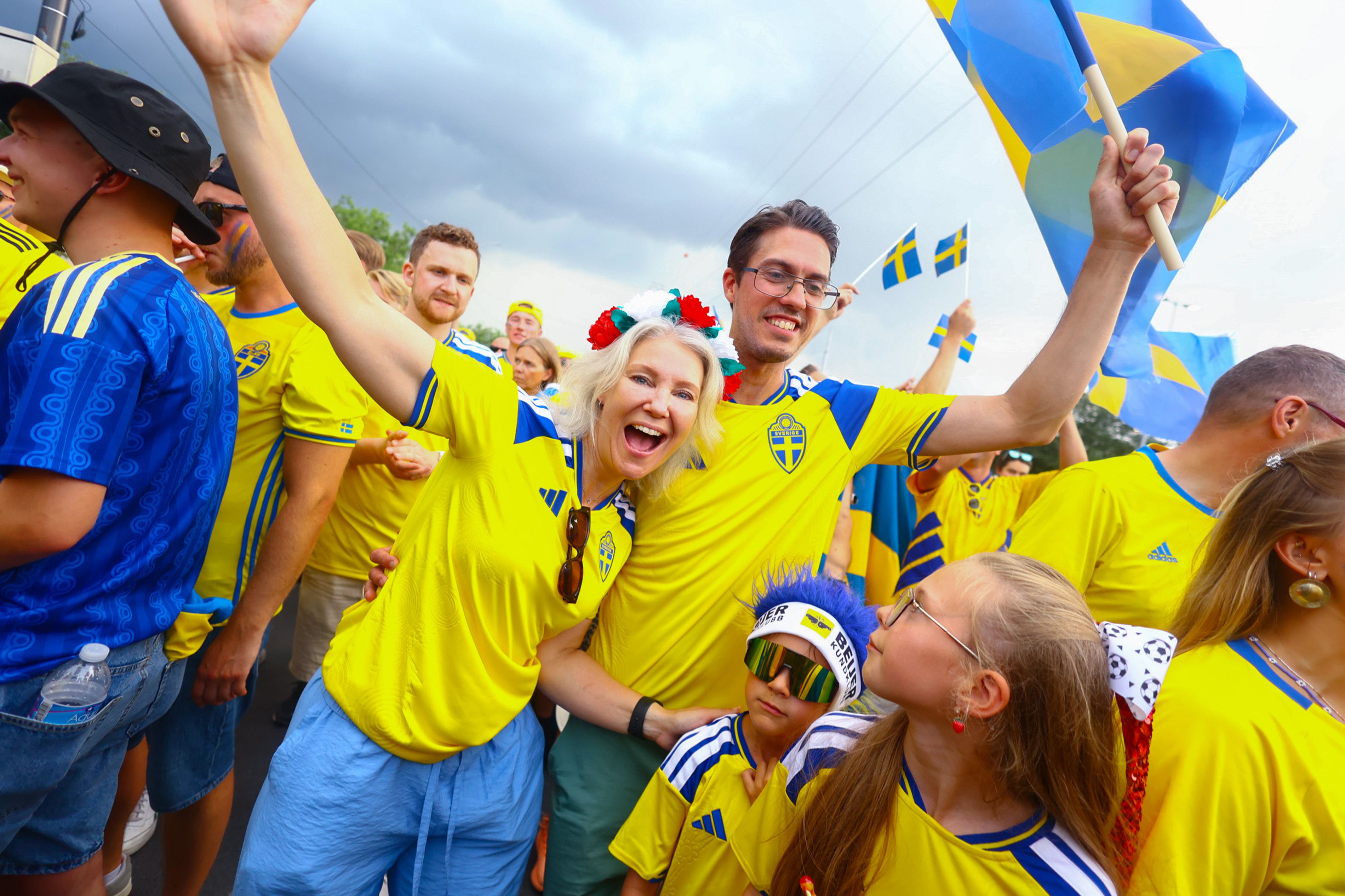 Sweden fans wearing yellow and blue, holding the Sweden flag.