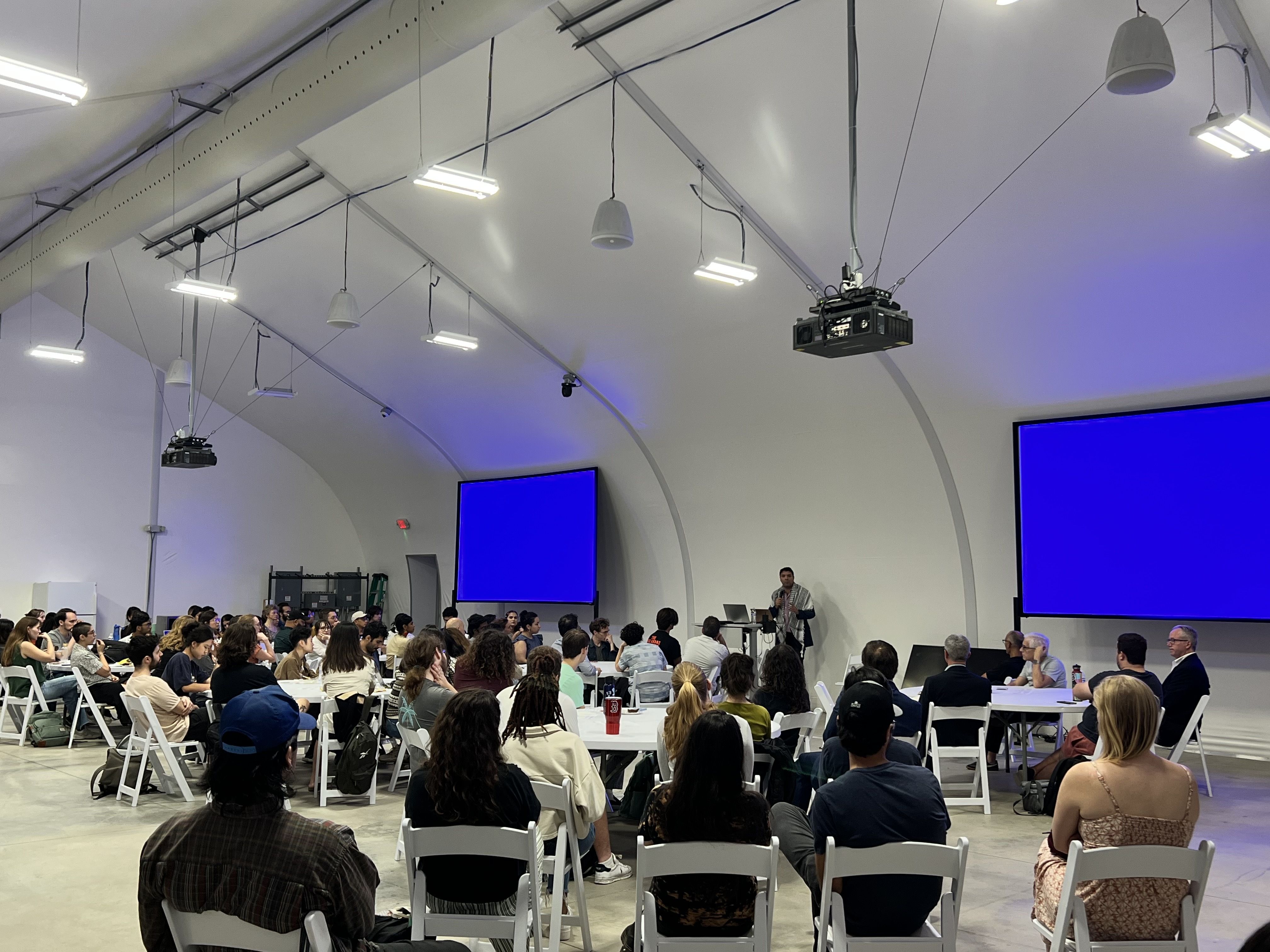Photo of a man in front of a seated crowd.