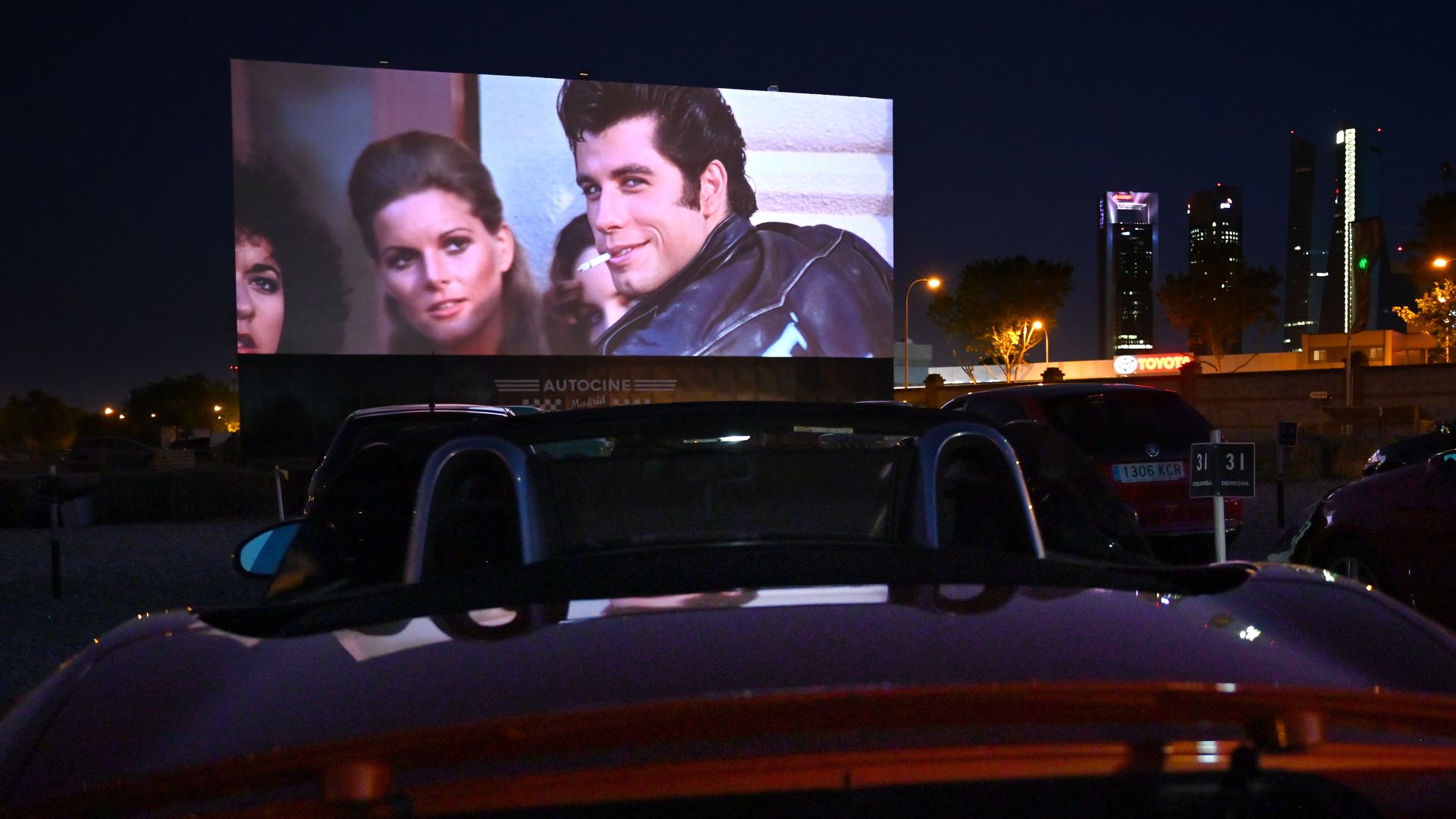 Car at a drive-in theater showing the movie "Grease." 