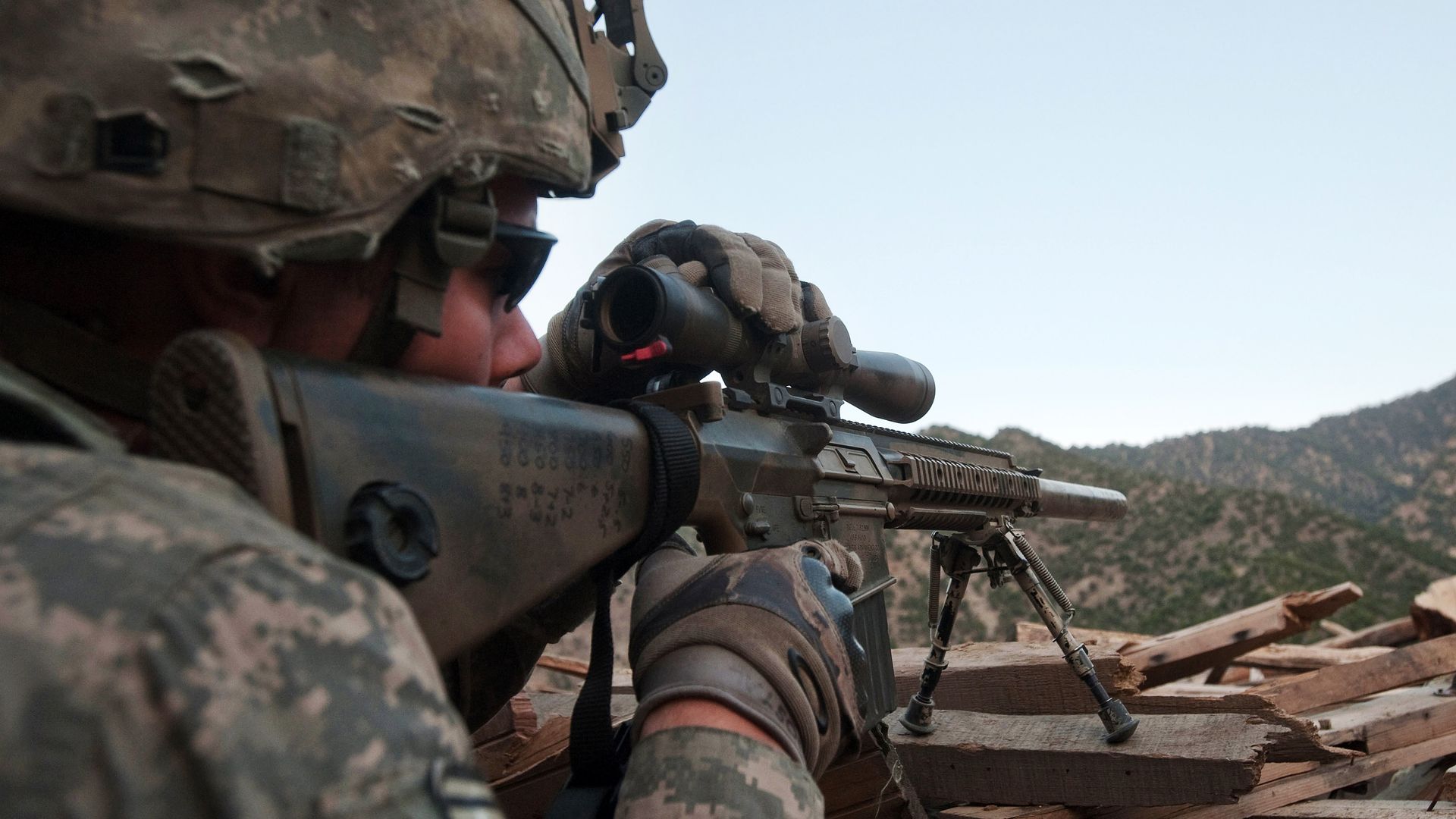 Photo of a soldier positioned away from the camera as they line up their sniper rifle