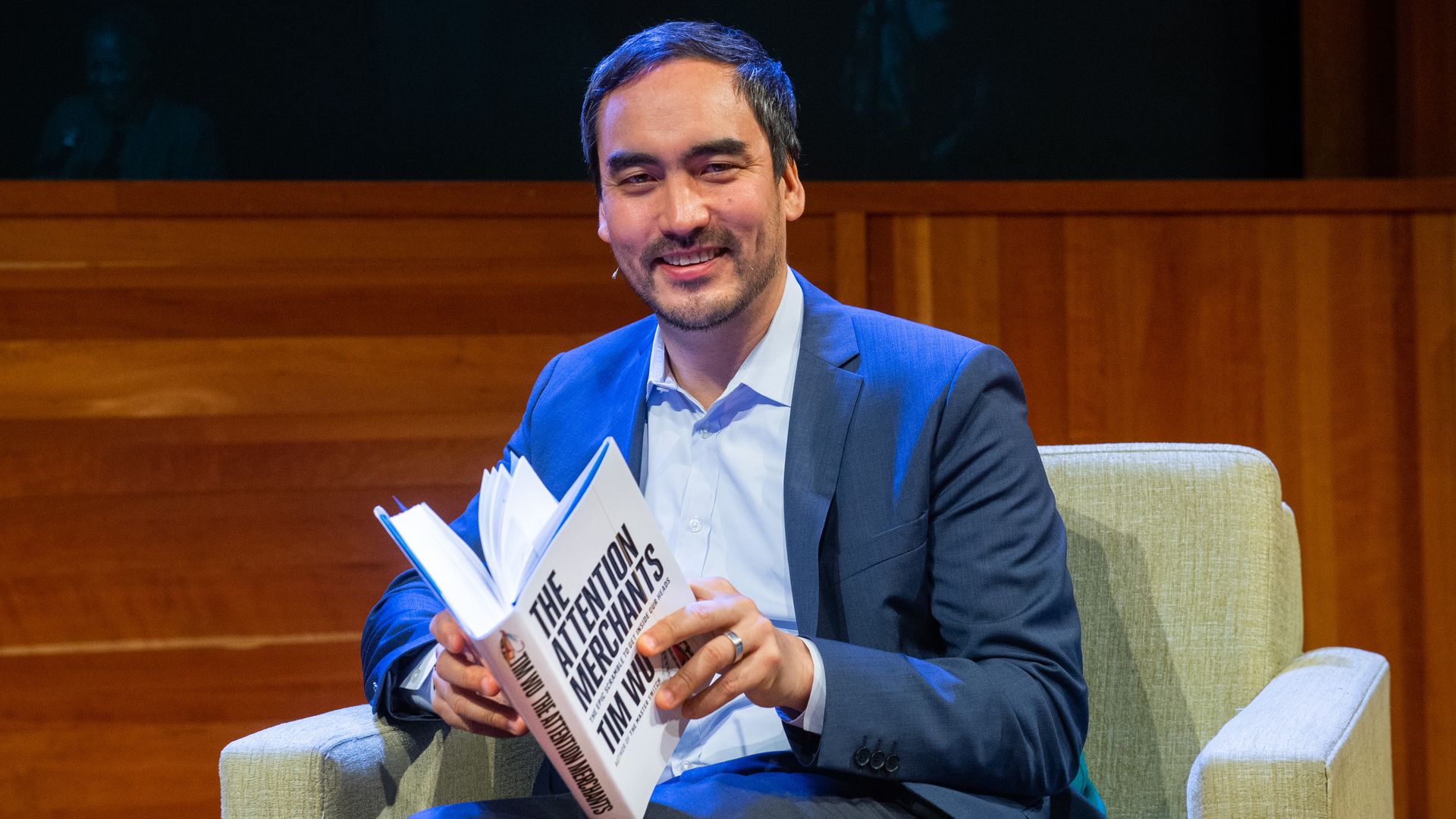 Departing White House antitrust official Tim Wu holding a book on stage