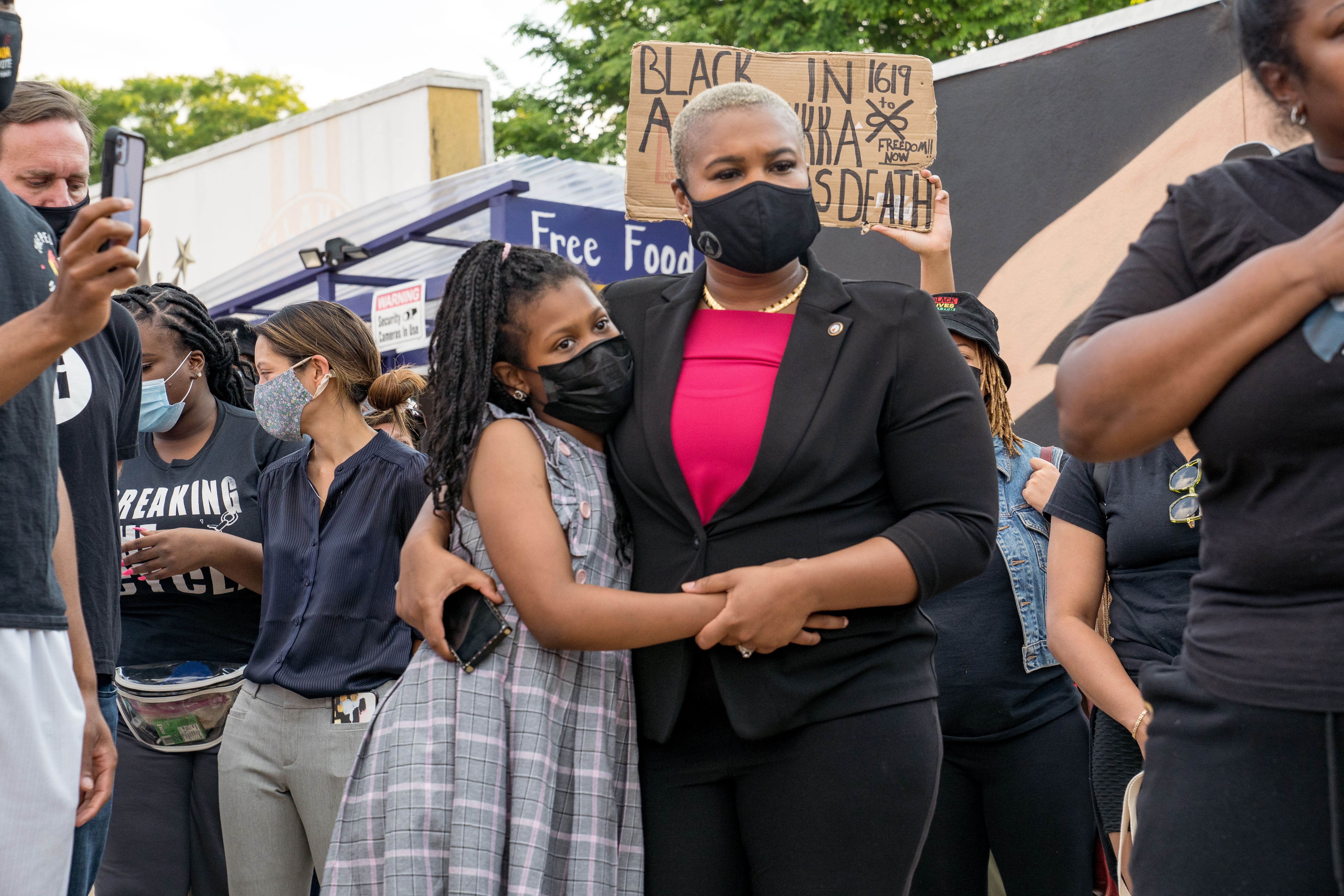 Georgia state representative Erica Thomas hugs her daughter while listening to speakers speak before marching through the streets after the verdict was announced