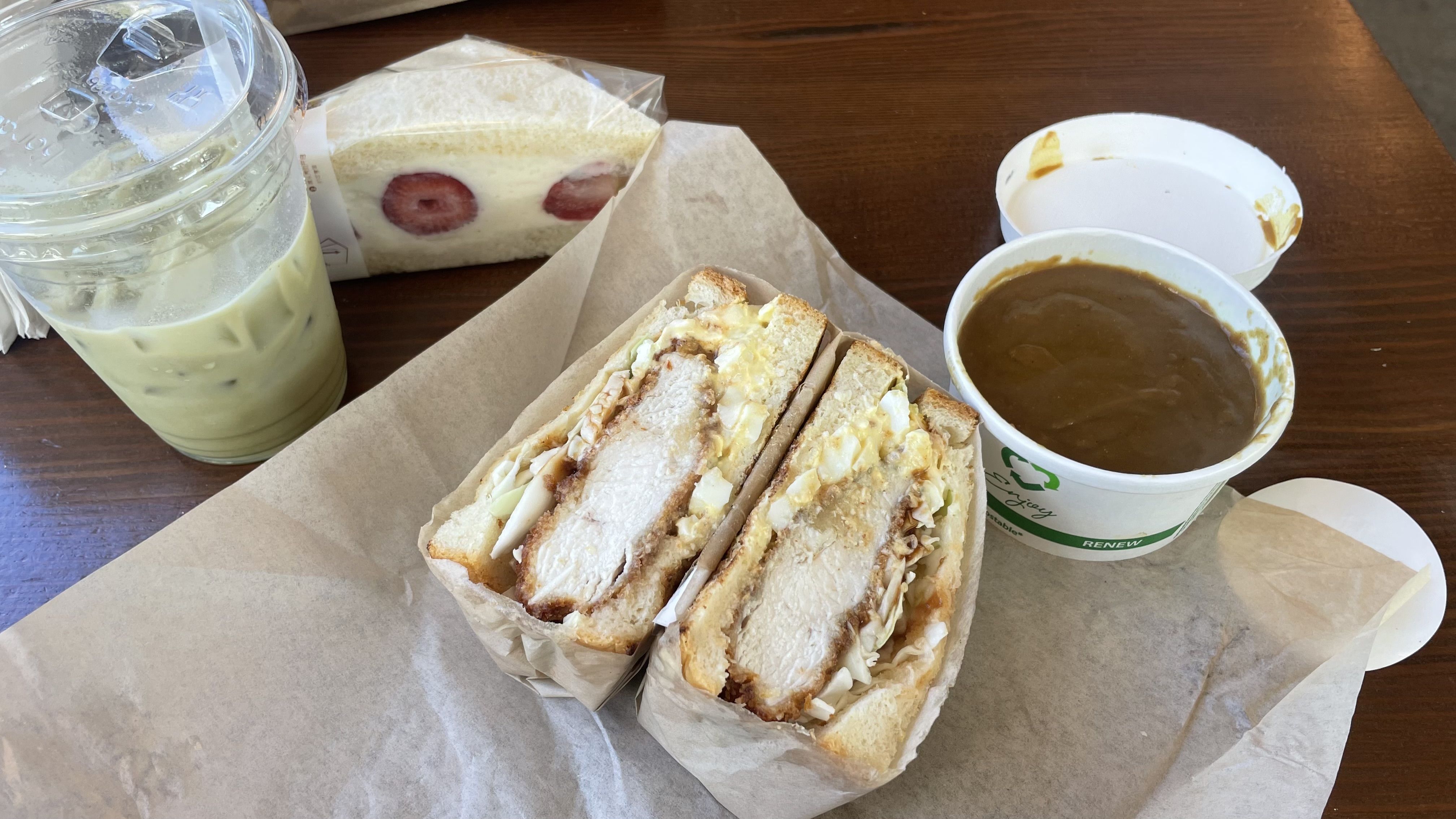 A photo of an open sandwich with a cup of curry beside it.