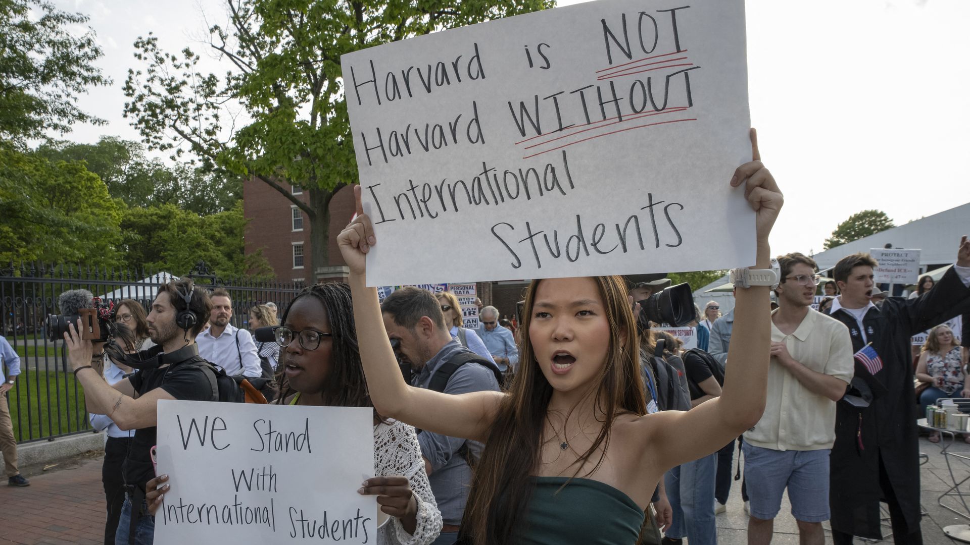 Woman holding sign for Harvard international students and others around her