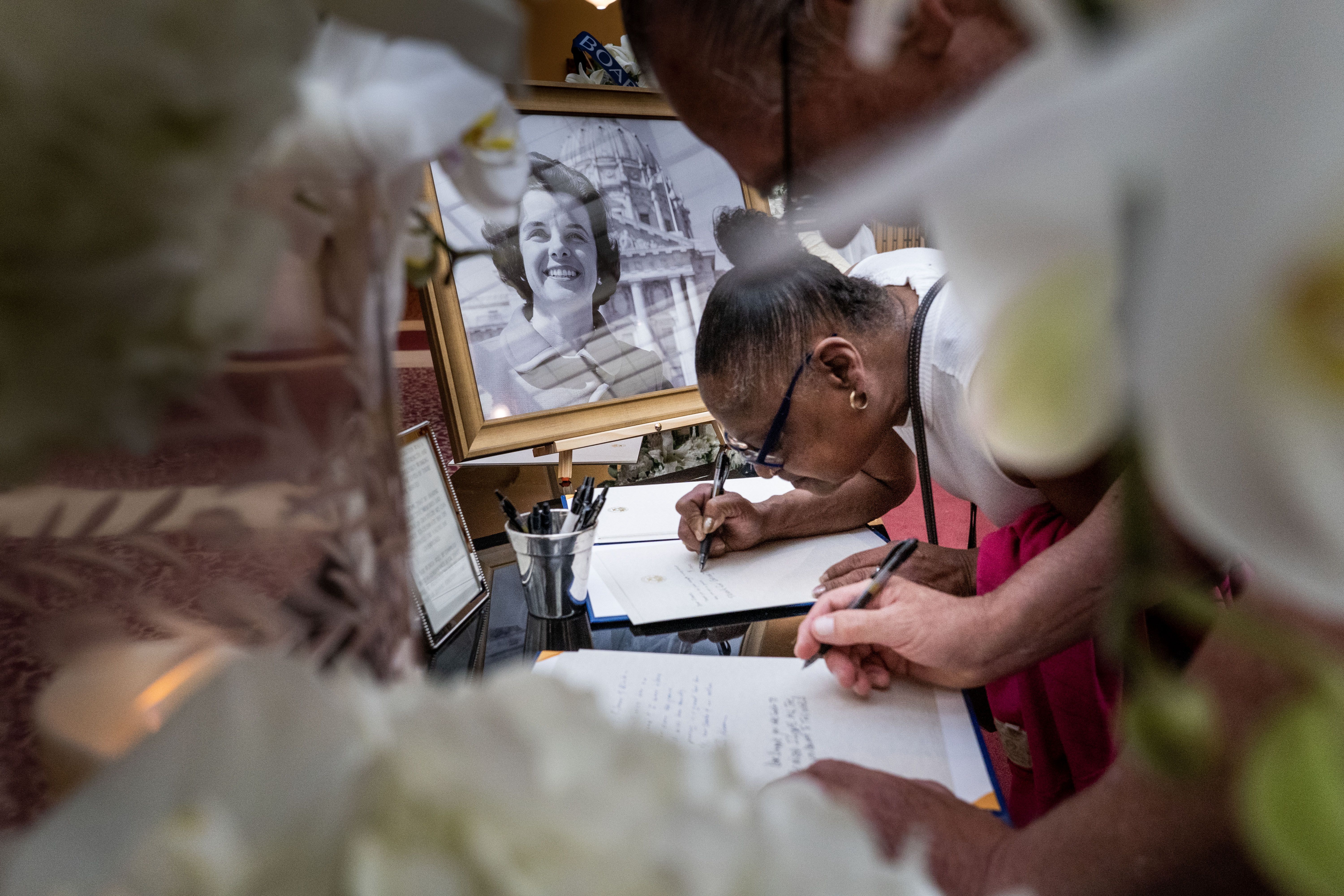 A woman writes a note addressed to Feinstein with a photo of a younger Feinstein in a picture frame 