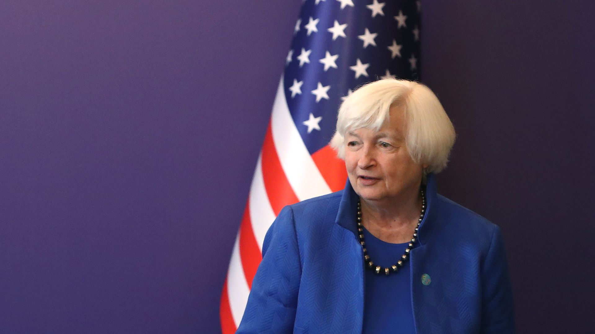 Janet Yellen standing next to an American flag