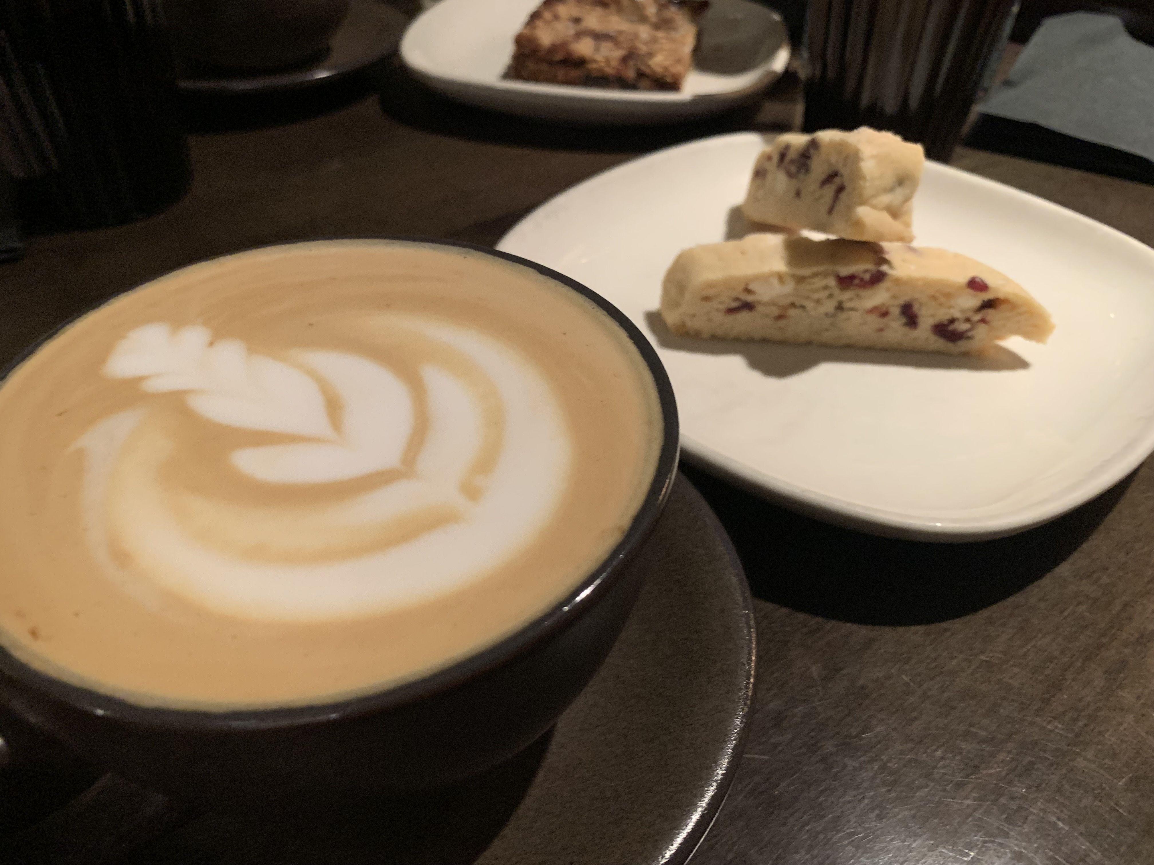 Photo of a cup of coffee with a flower drawn in the latte foam. 