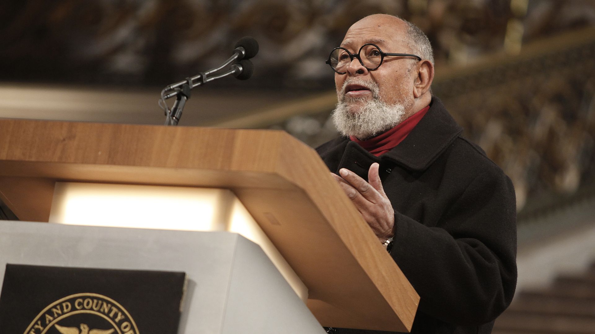 Photo of Cecil Williams speaking from a podium at City Hall