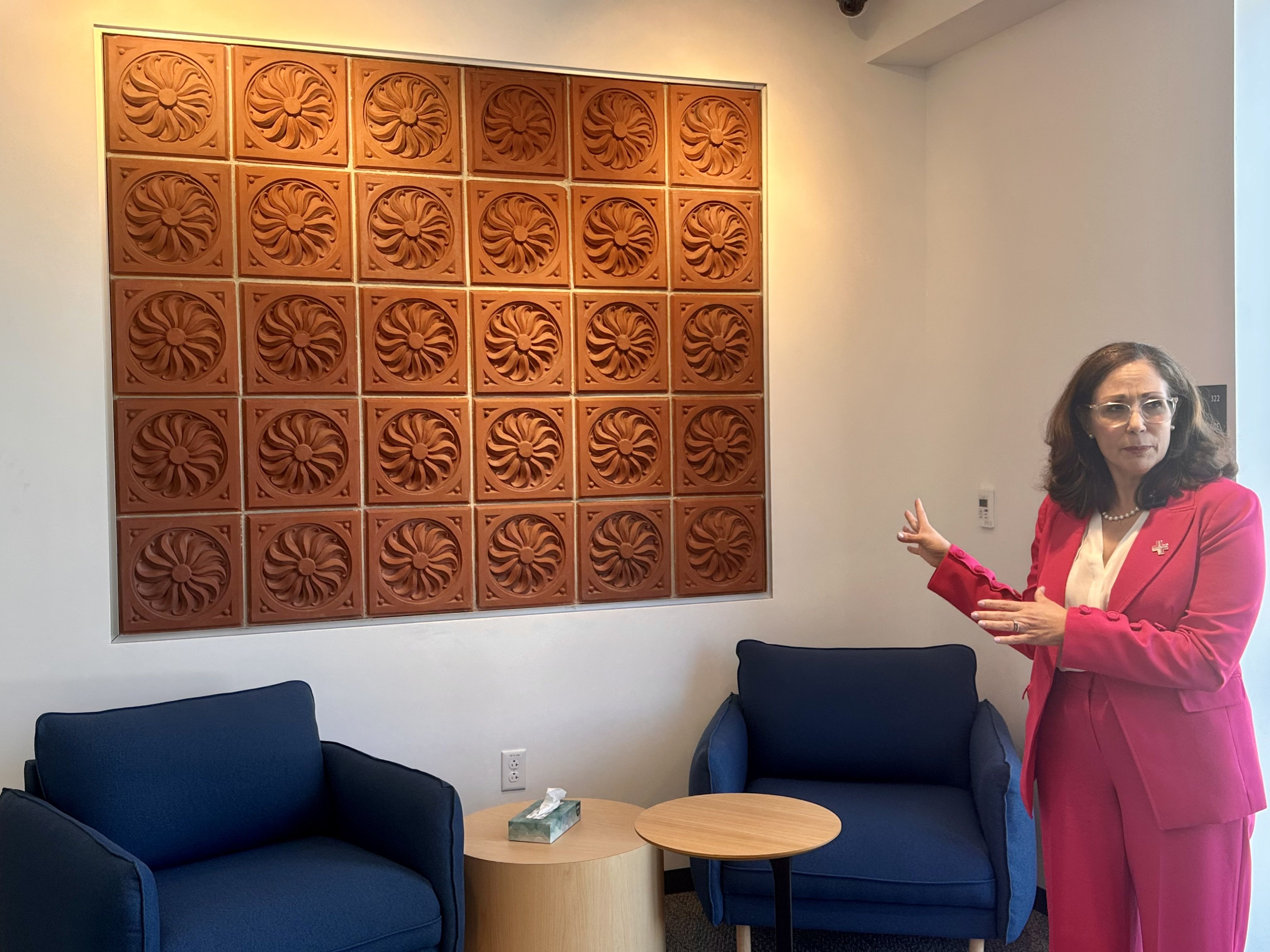 Vanessa Calderón-Rosado, IBA's CEO, stands in front of a terracotta installation on the wall of La CASA's second-floor lobby and explains that the terracotta tiles came from the original church building.