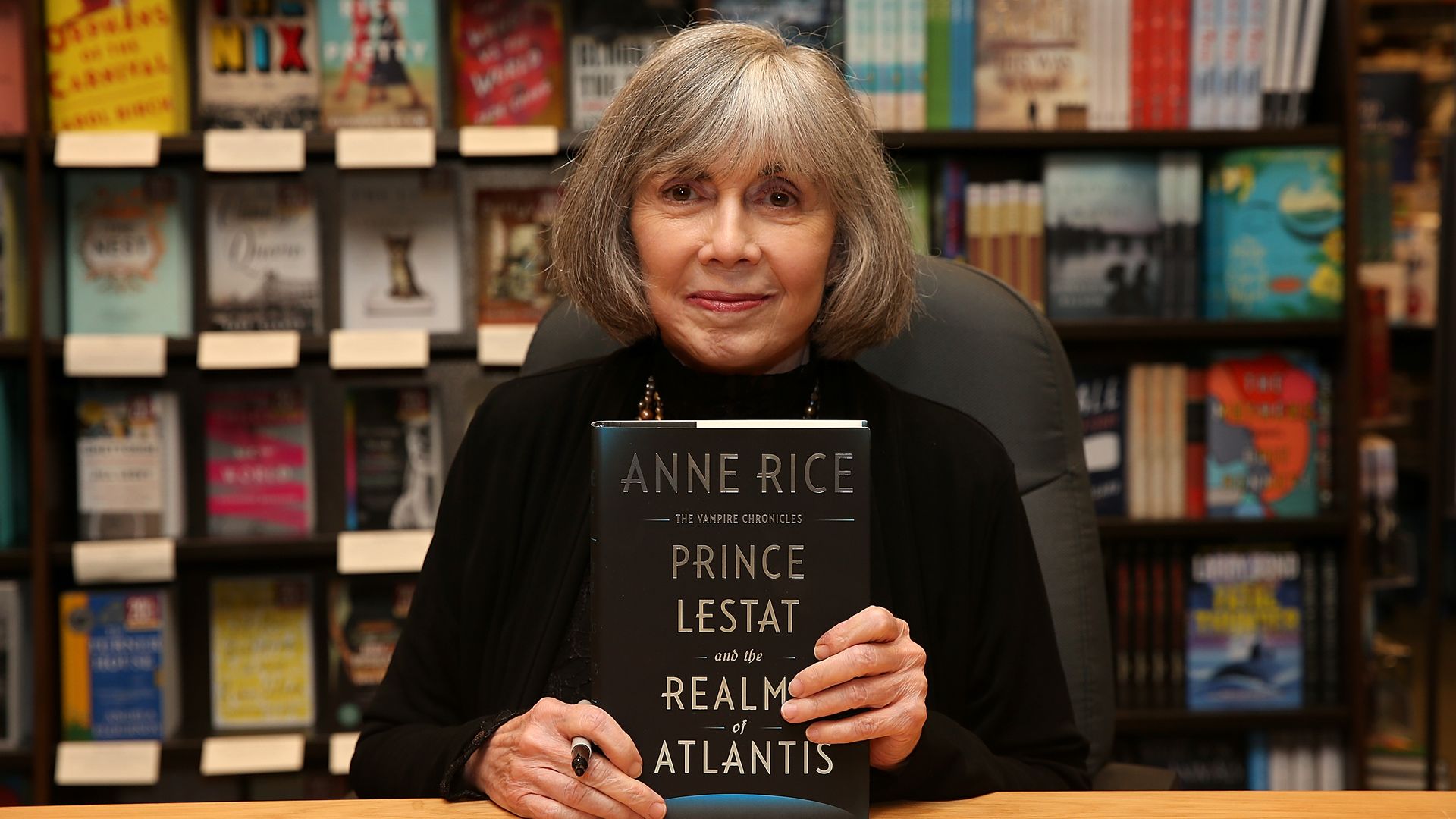 Anne Rice poses with a book. Her name is on the front, along with "Prince Lestat."