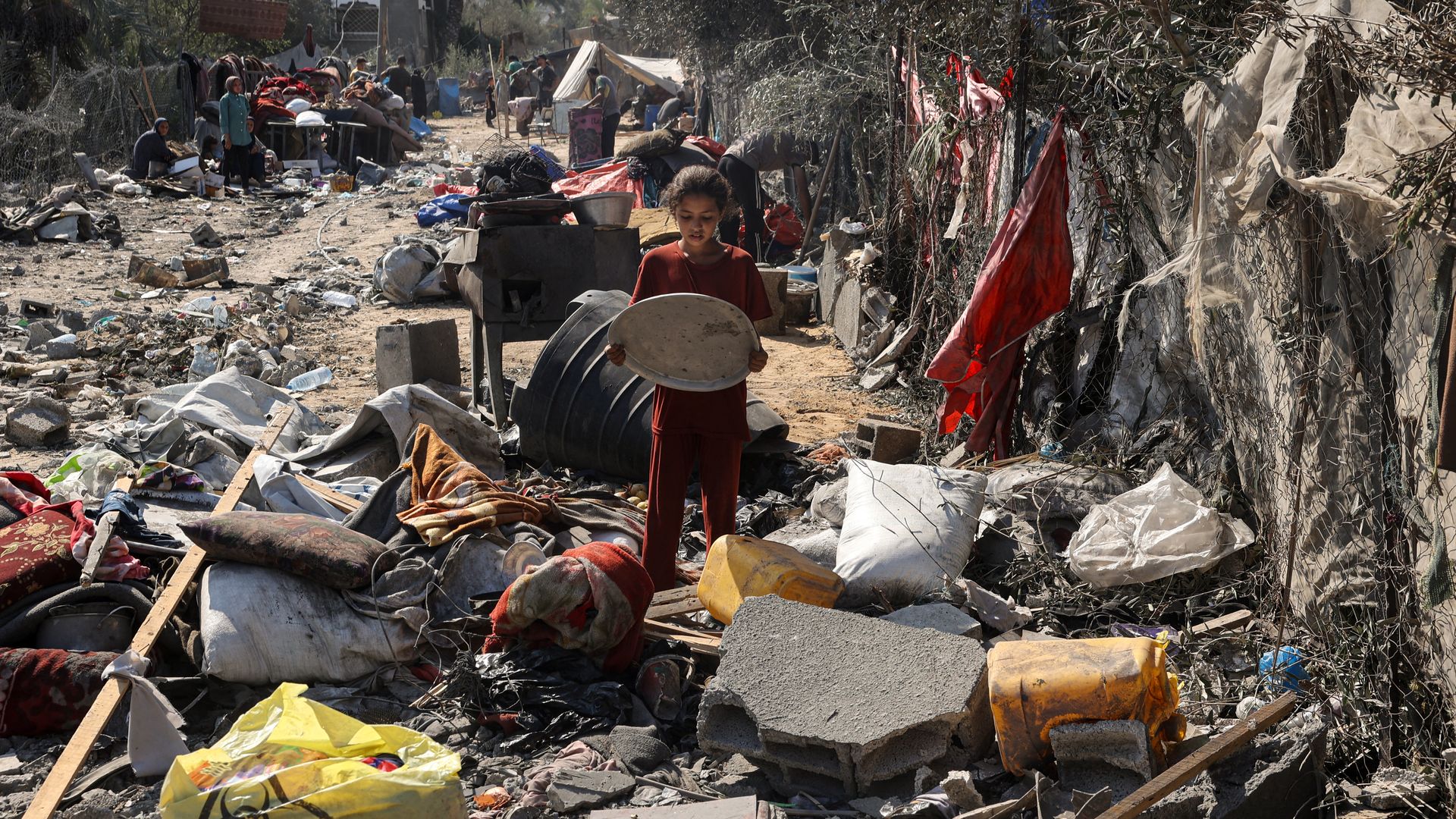 A Palestinian girl recovers a tray from items scattered on the floor in Deir el-Balah in the central Gaza Strip, on August 7, 2024,