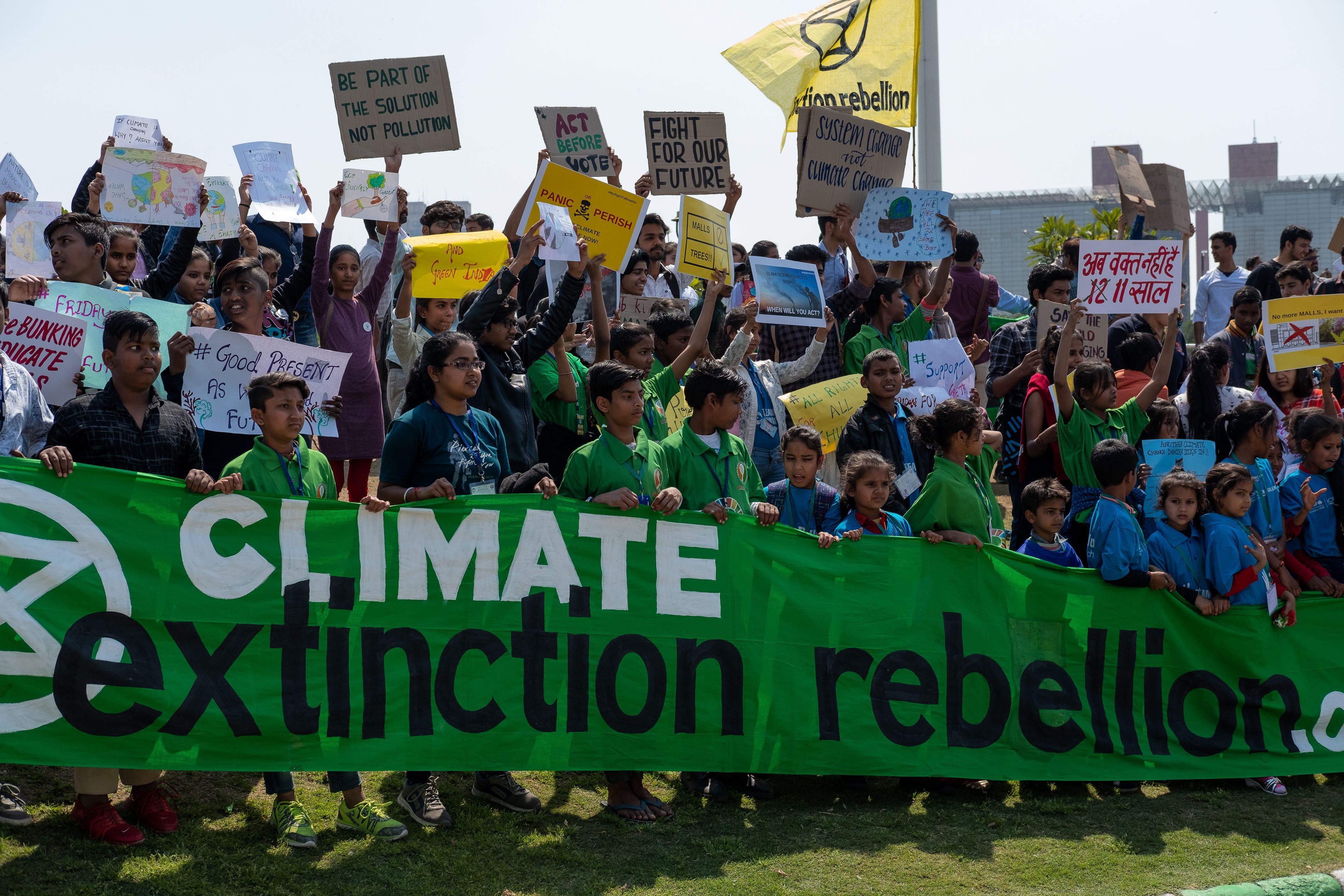Students and children hold a large green banner that reads "climate extinction rebellion"