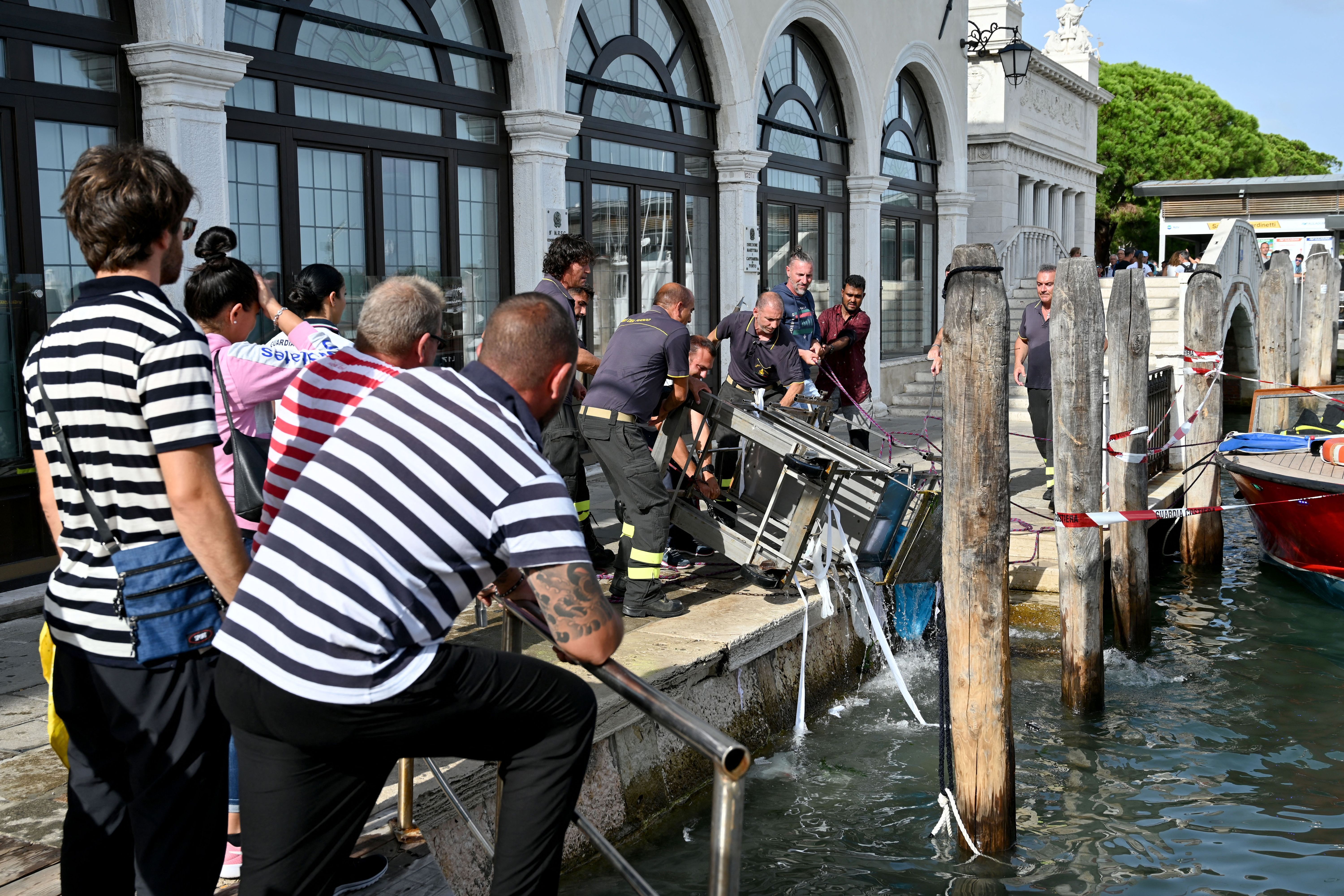 Firefighters recover a Souvenirs stall that ended up in the Grand Canal in Venice due to strong winds, on August 18.