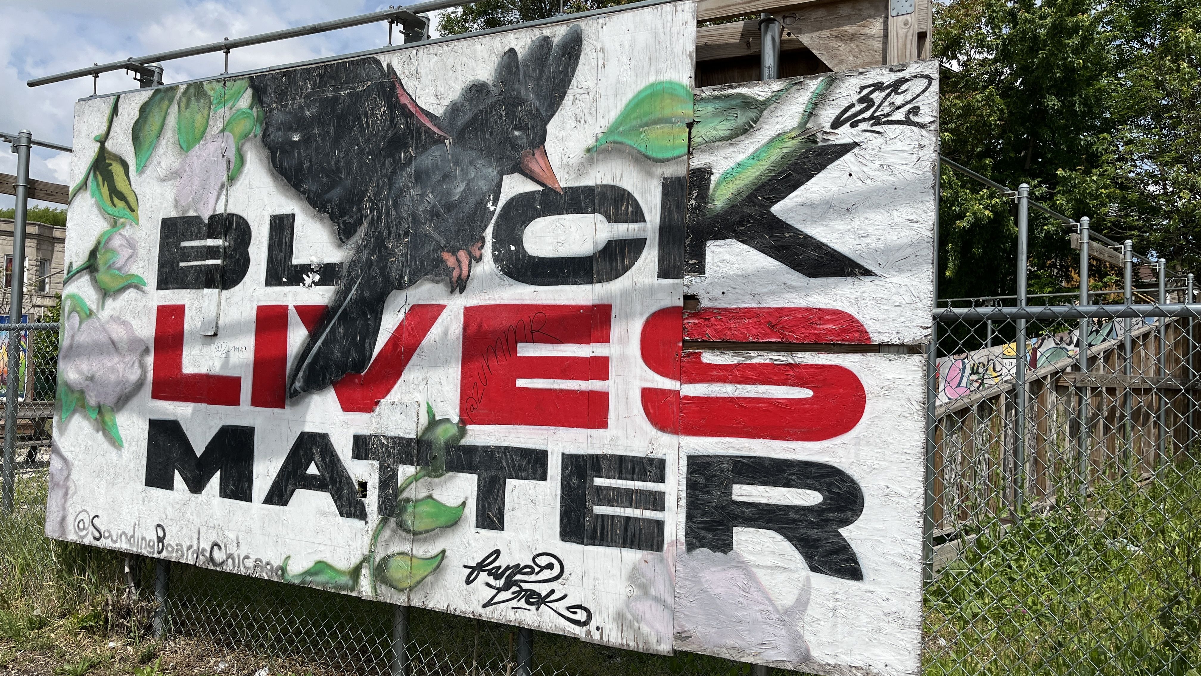 Black Lives Matter art on a wooden board with a crow sitting on it.
