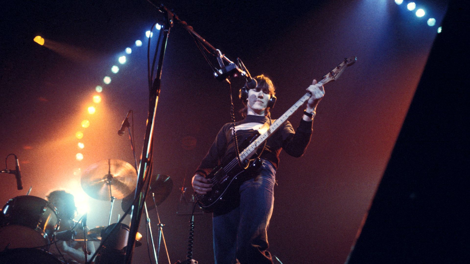 Roger Waters of Pink Floyd plays bass on stage in the 1970s. 
