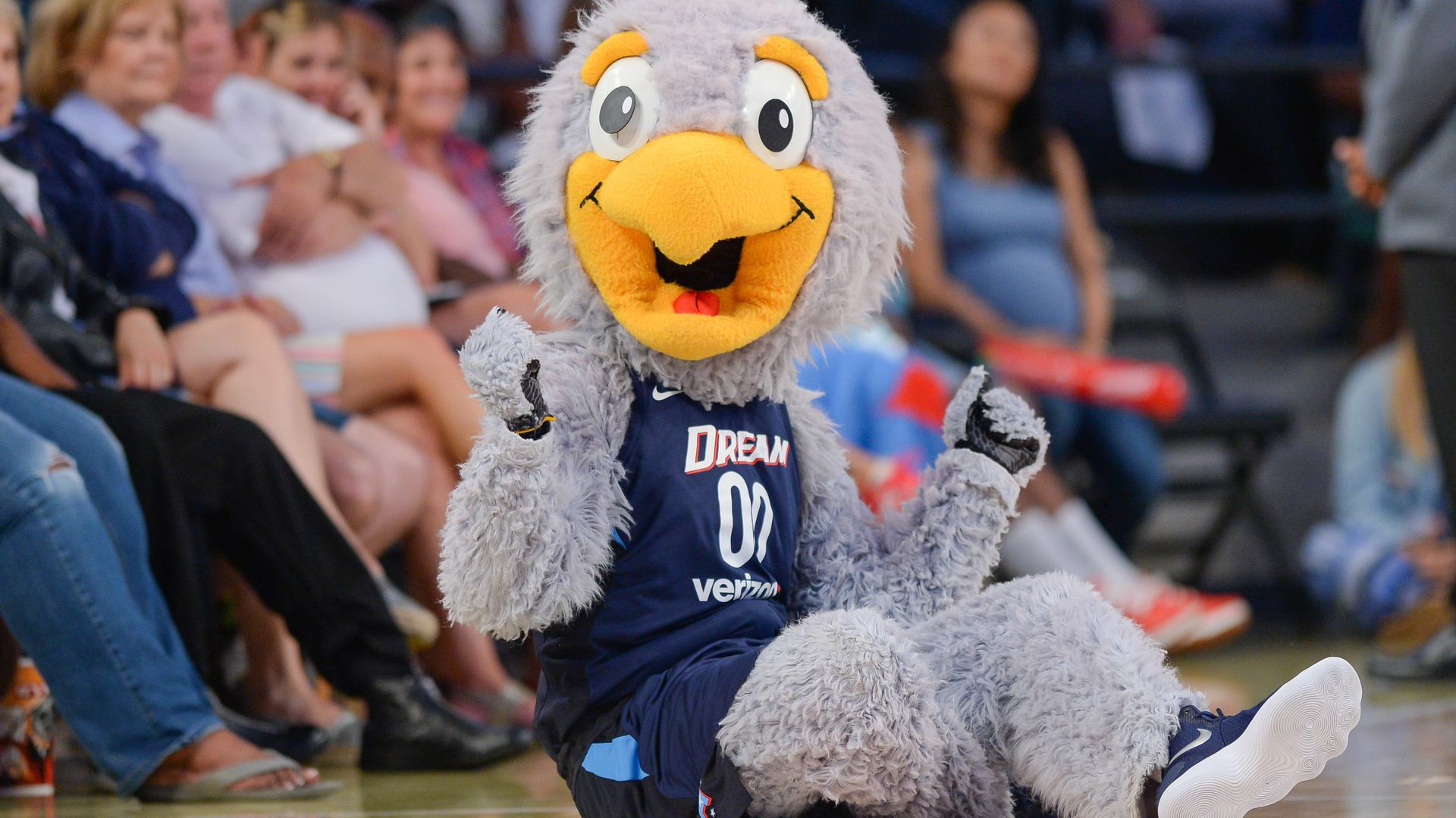 A grey bird mascot wears an Atlanta Dream uniform on the sideline of a WNBA game