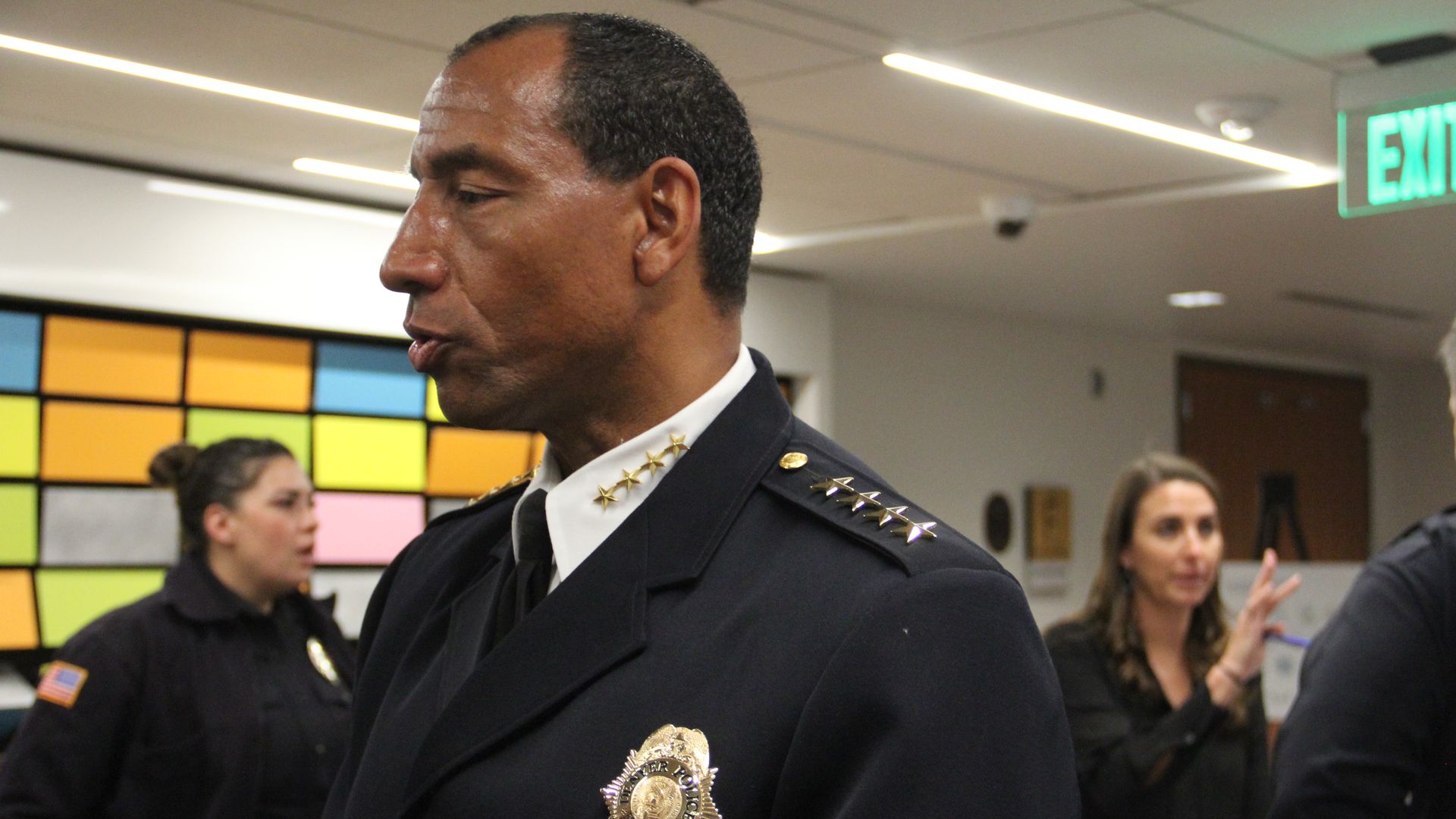 A man in a black police uniform speaks to someone.