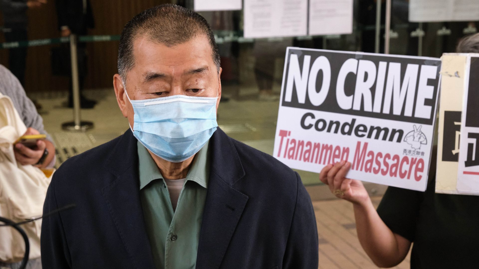 A supporter holds a placard highlighting the Tiananmen Massacre as pro-democracy media tycoon Jimmy Lai arrives at West Kowloon Magistrates' Court in  Hong Kong