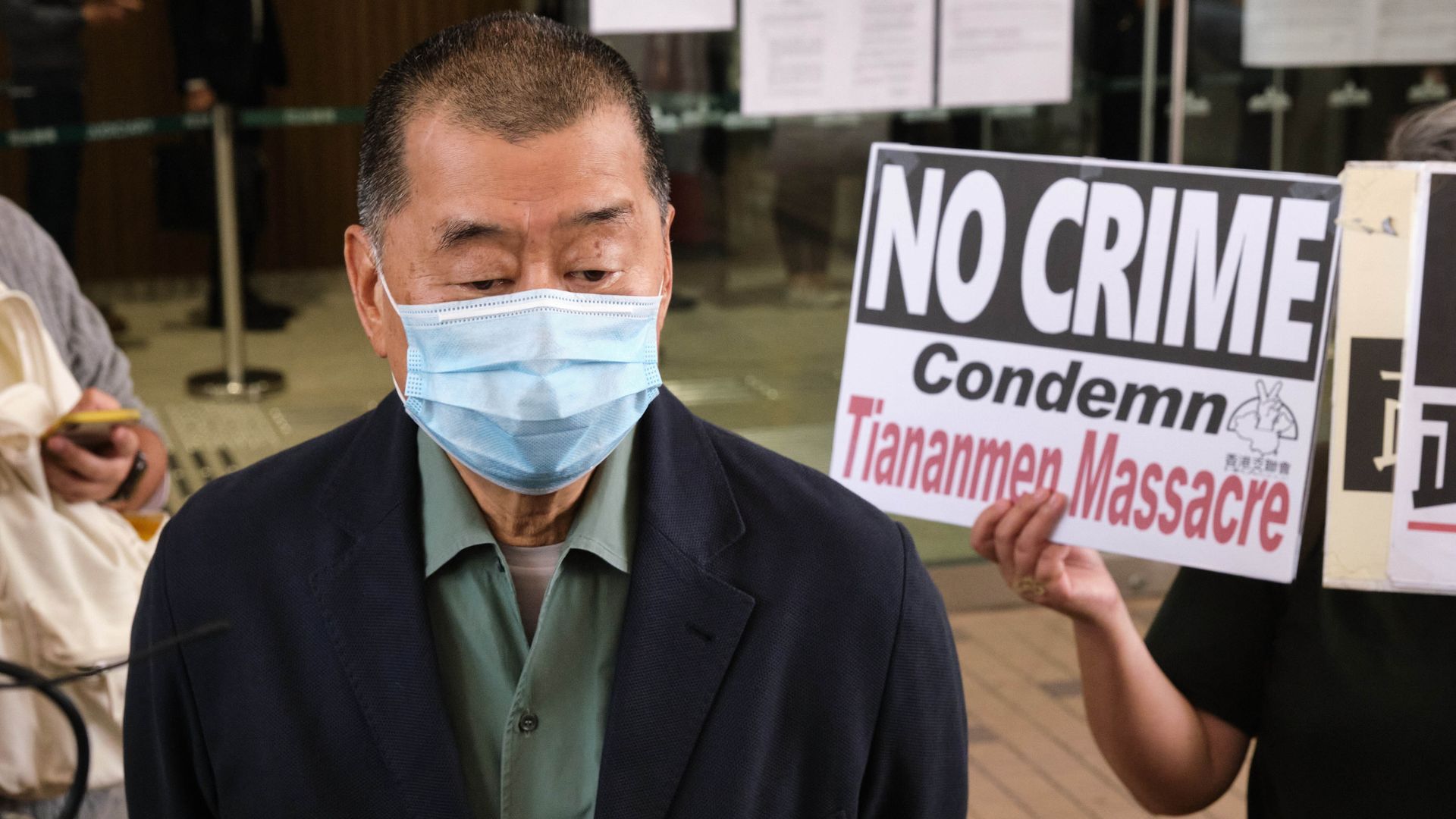 A supporter holds a placard highlighting the Tiananmen Massacre as pro-democracy media tycoon Jimmy Lai arrives at West Kowloon Magistrates' Court in Hong Kong