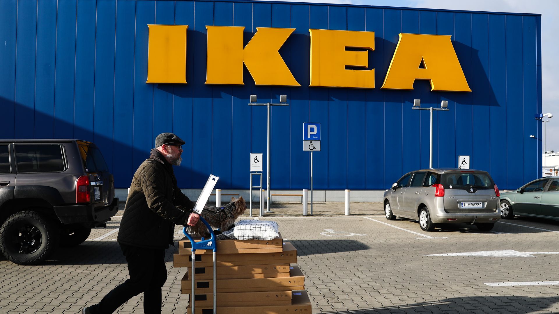 A man with a shopping trolley and a dog passes by the Ikea shop in Krakow, Poland 