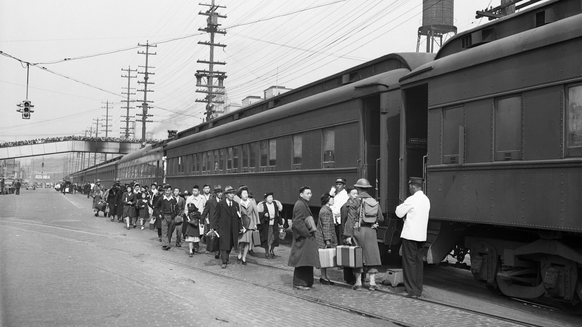 Japanese Americans board a train in Seattle in 1942 as onlookers watch. 