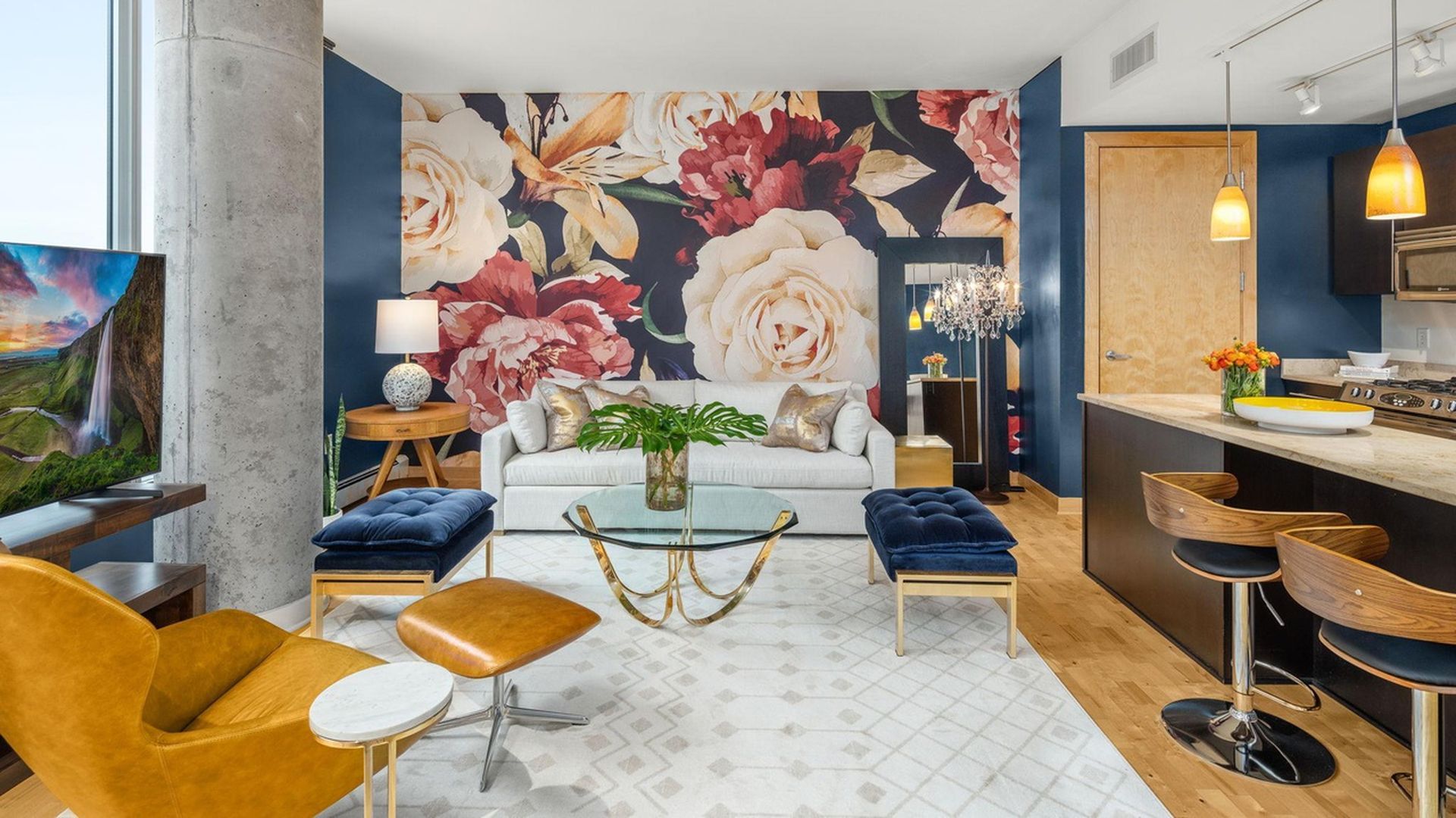 A living room with a bright floral mural on the wall and navy furniture.