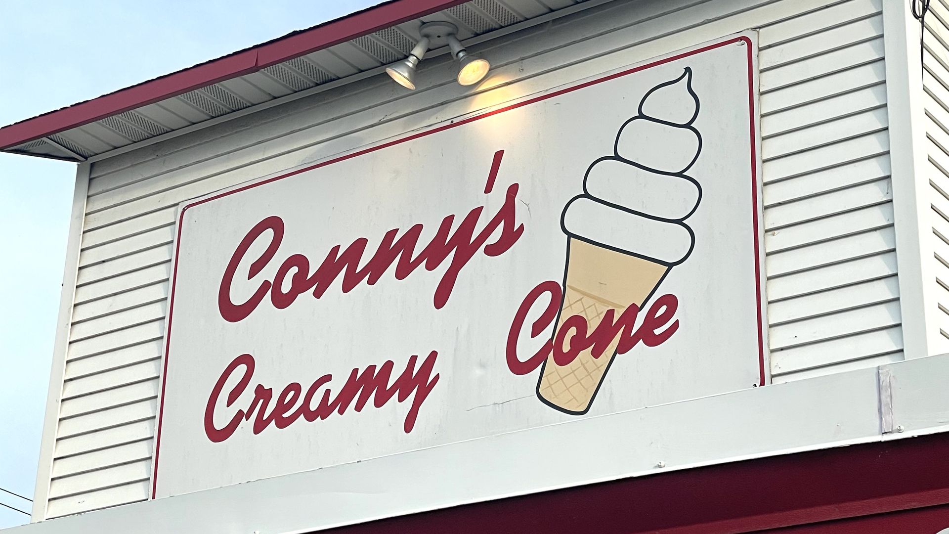 A red and white sign that reads Conny's Creamy Cone.