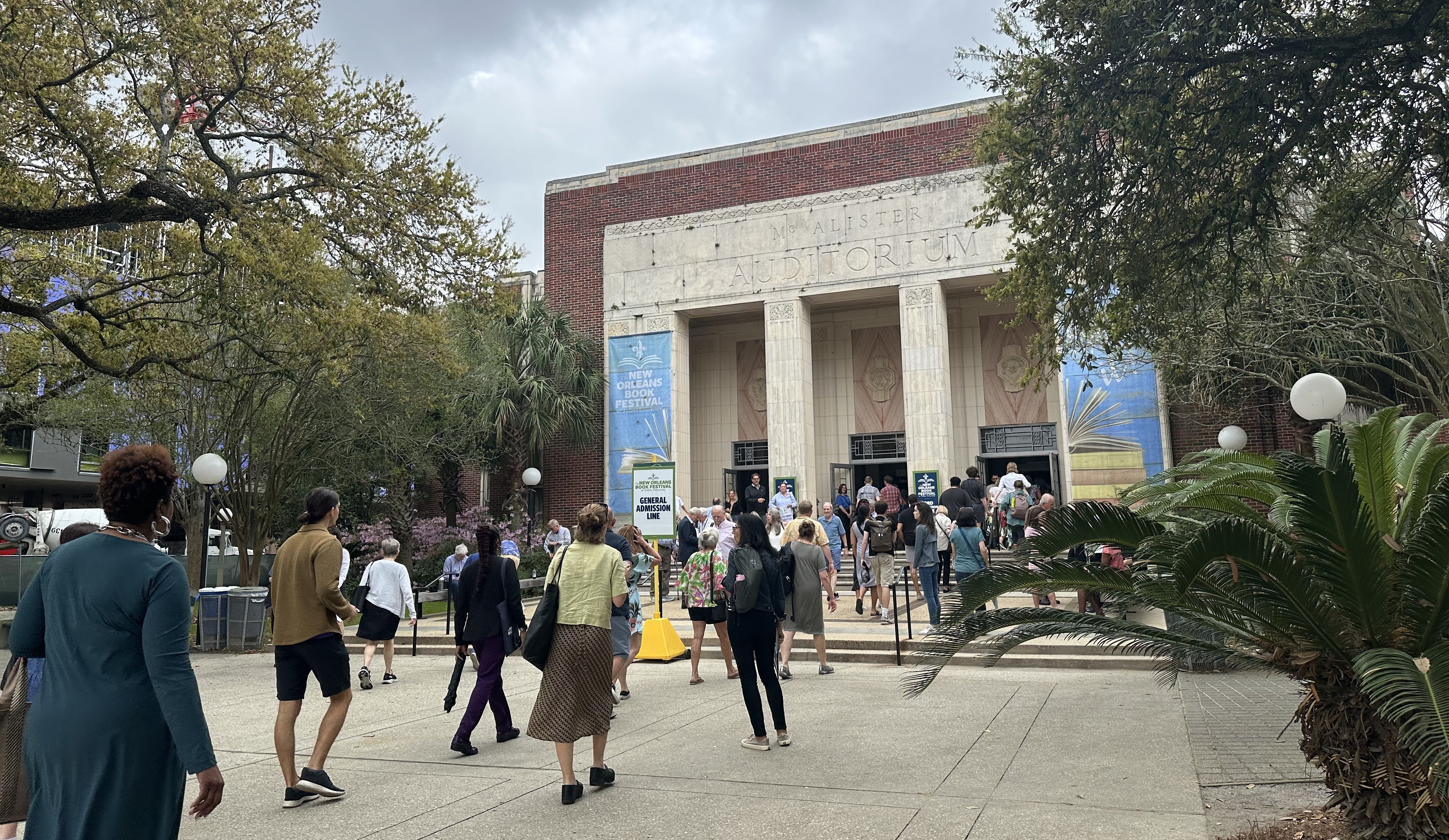 People walk in and out of a building with the name McAlister Auditorium. 