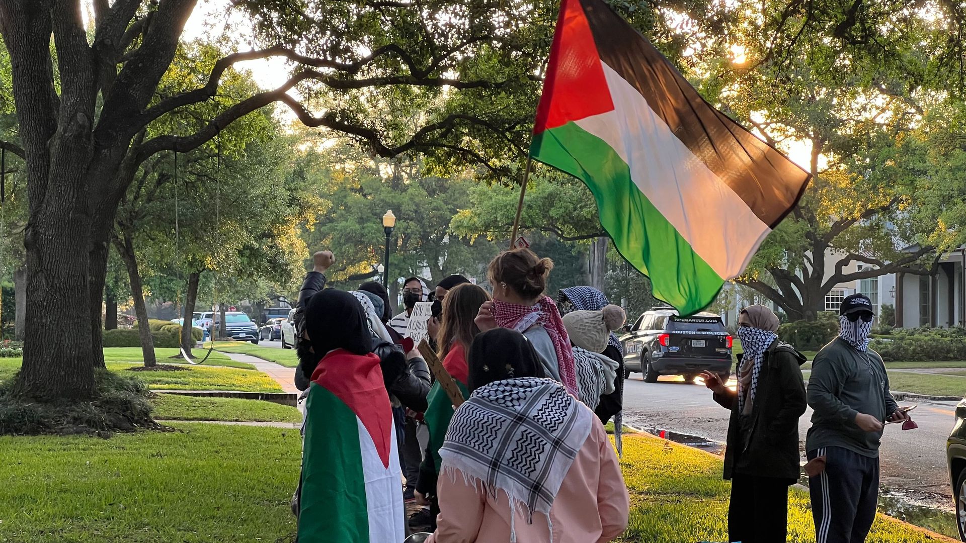 Photo of a group of people, with Palestine's flag, gathering in a neighborhood. 