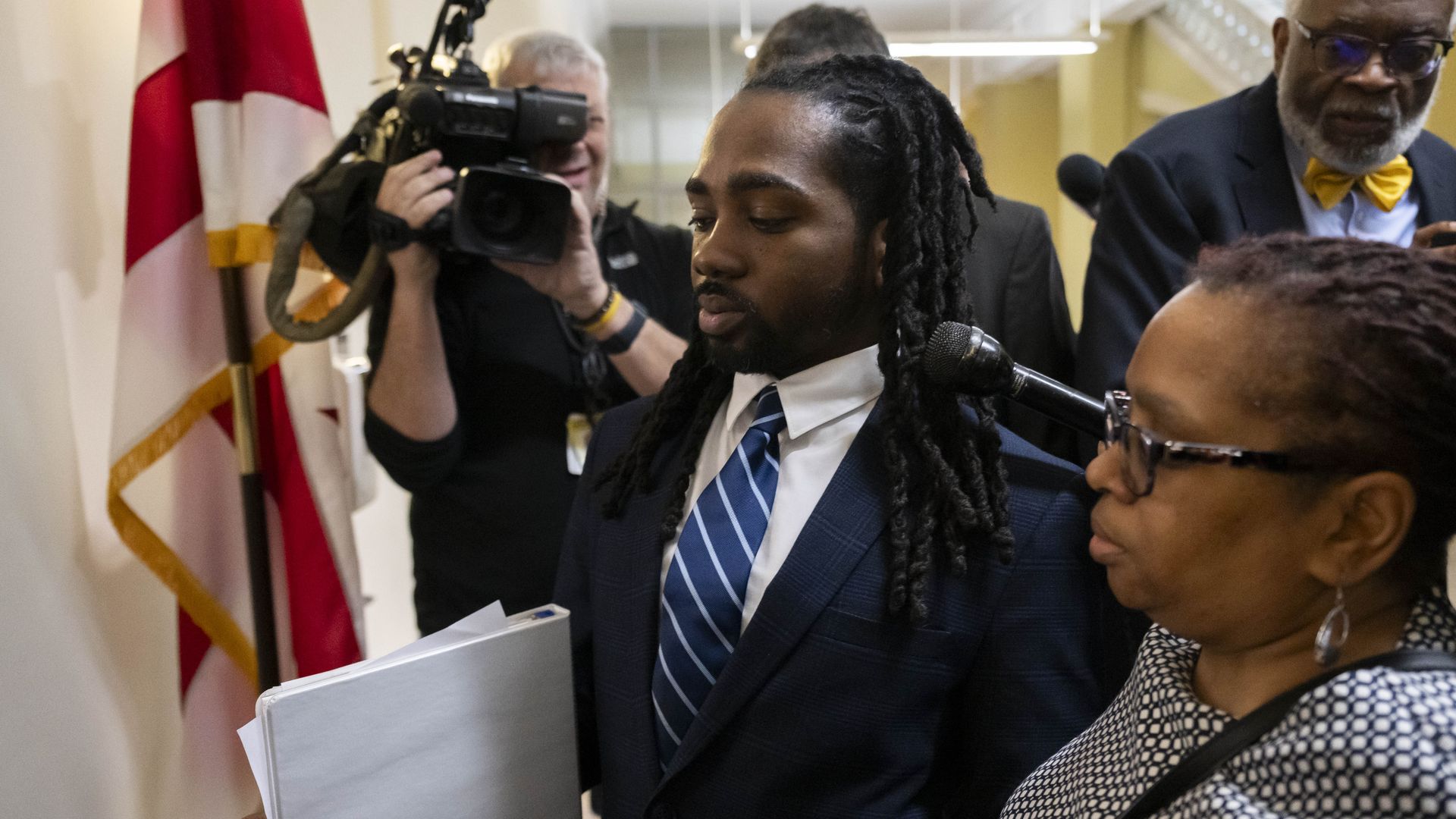 Trayon White is swarmed by reporters and TV cameras as he walks in a Wilson Building hallway