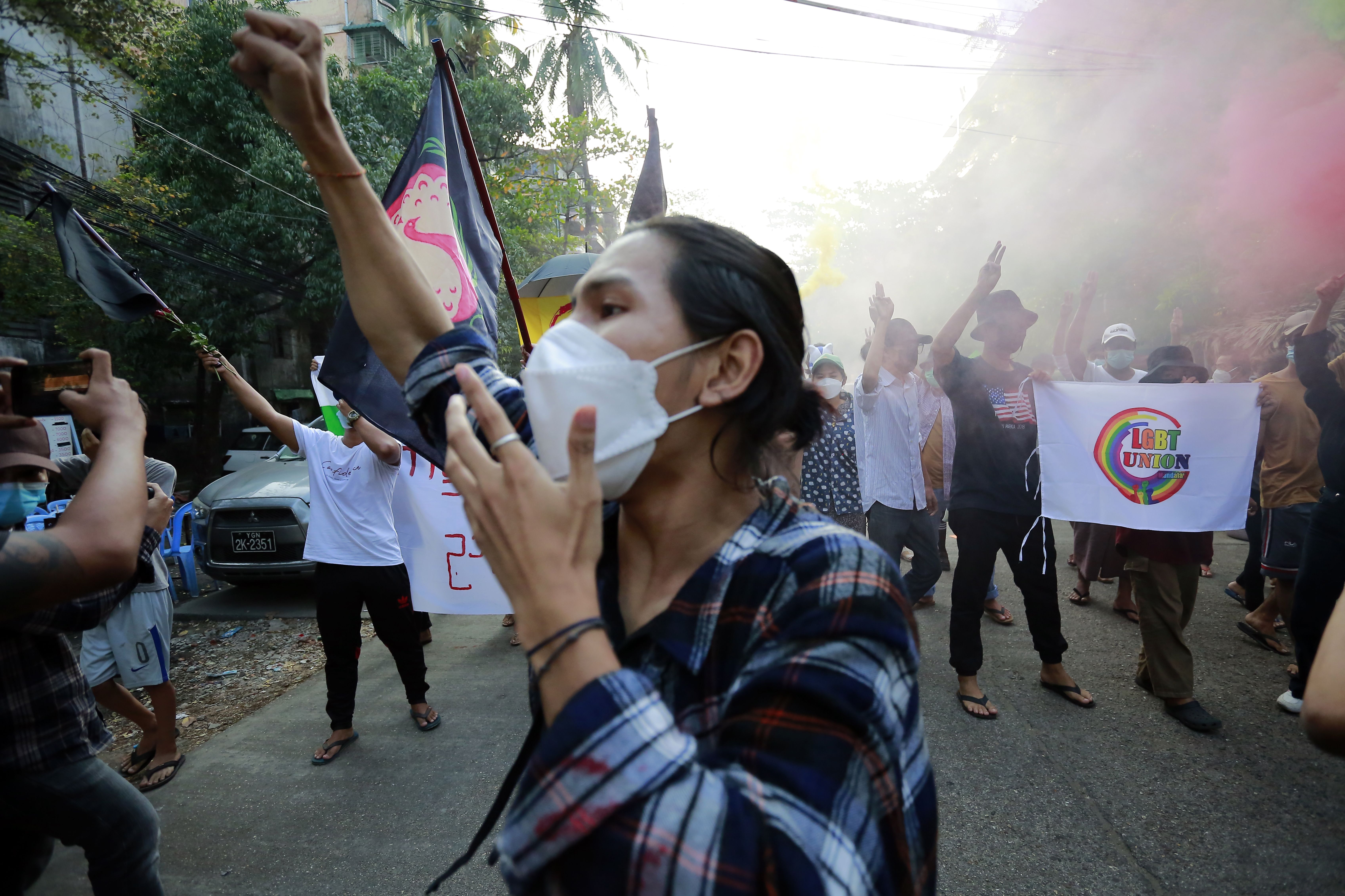 Les manifestants font le salut provocateur à trois doigts et tiennent des fusées éclairantes alors qu'ils défilent lors d'une manifestation contre le coup d'État militaire à Yangon, au Myanmar, le 3 mars. 