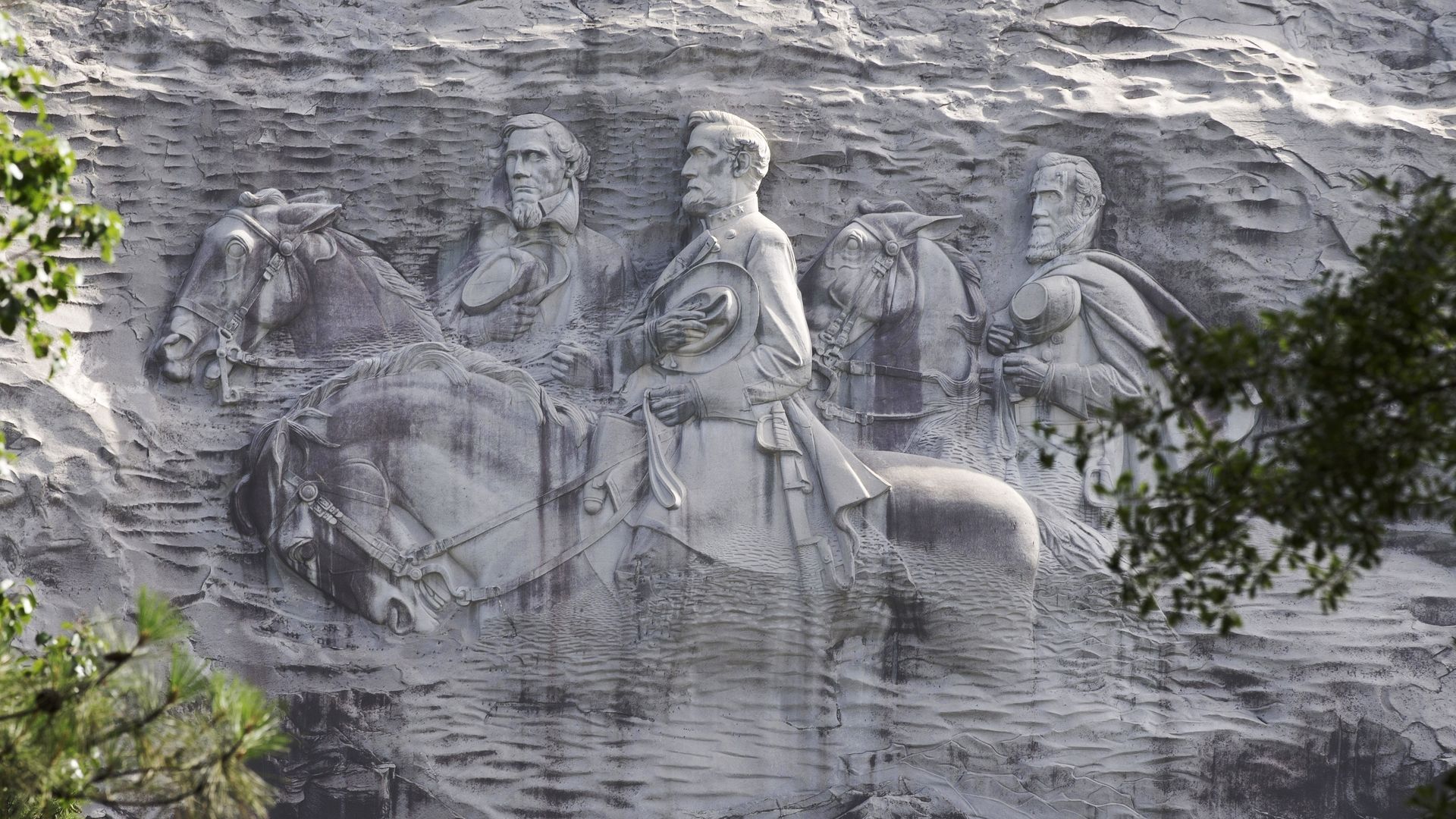 A photo of a large carving on the side of a stone mountain of Confederates riding horses