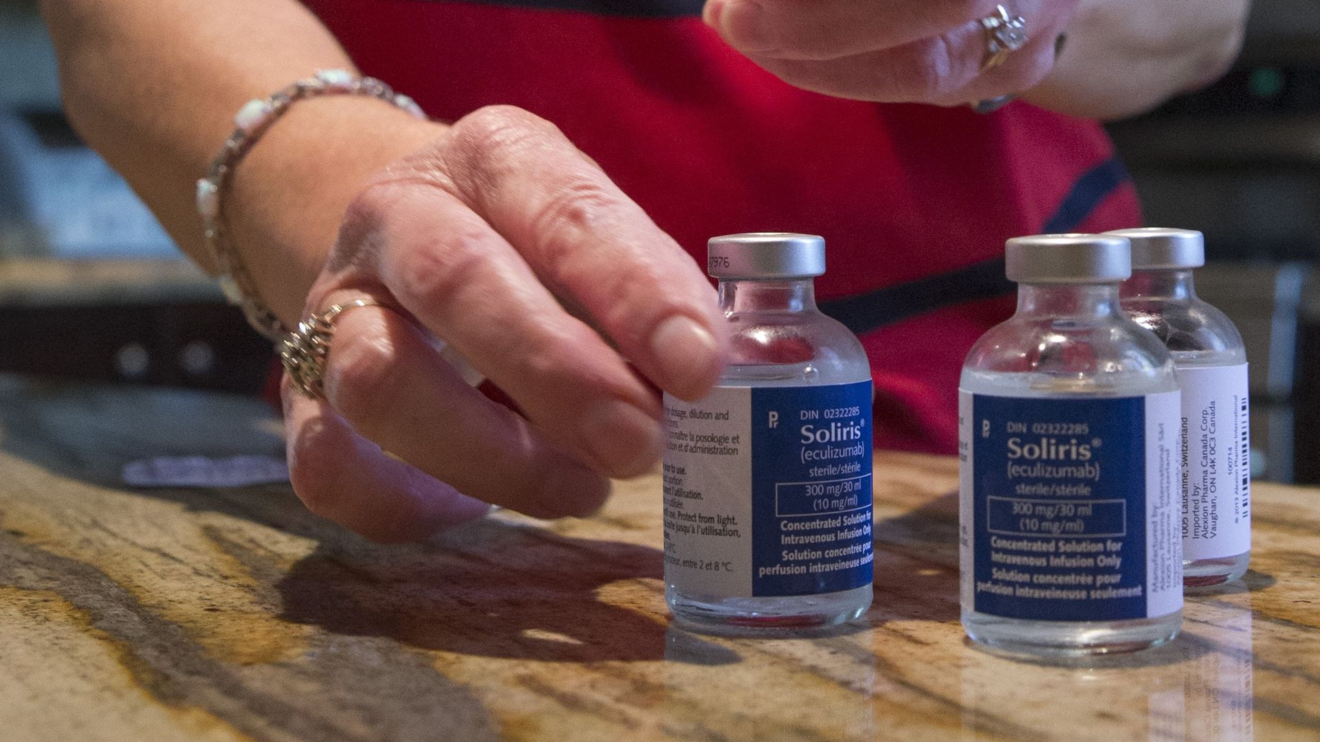 A nurse prepares vials of the drug Solaris on a table.