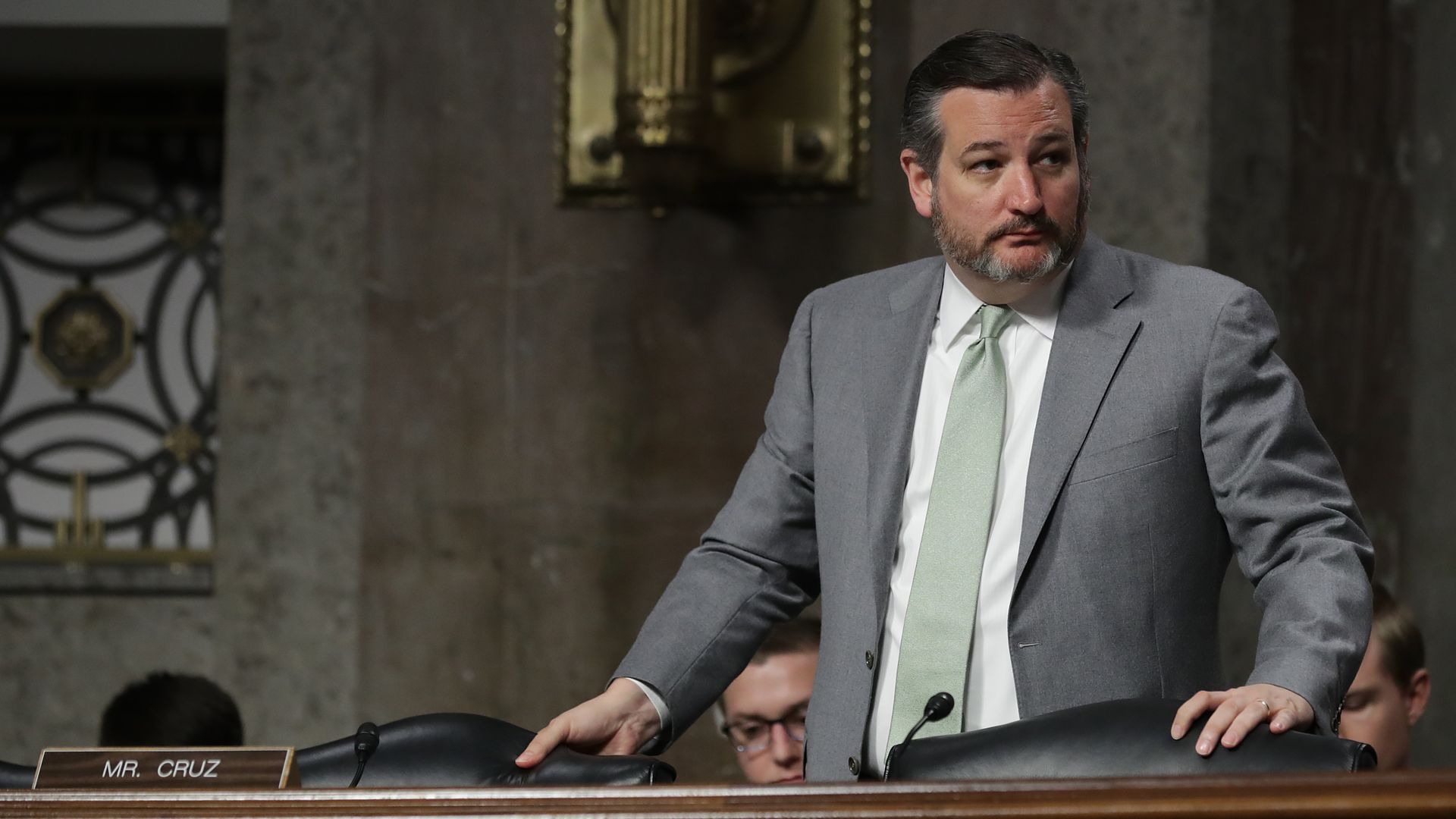 Ted Cruz stands at a hearing in a gray suit. 