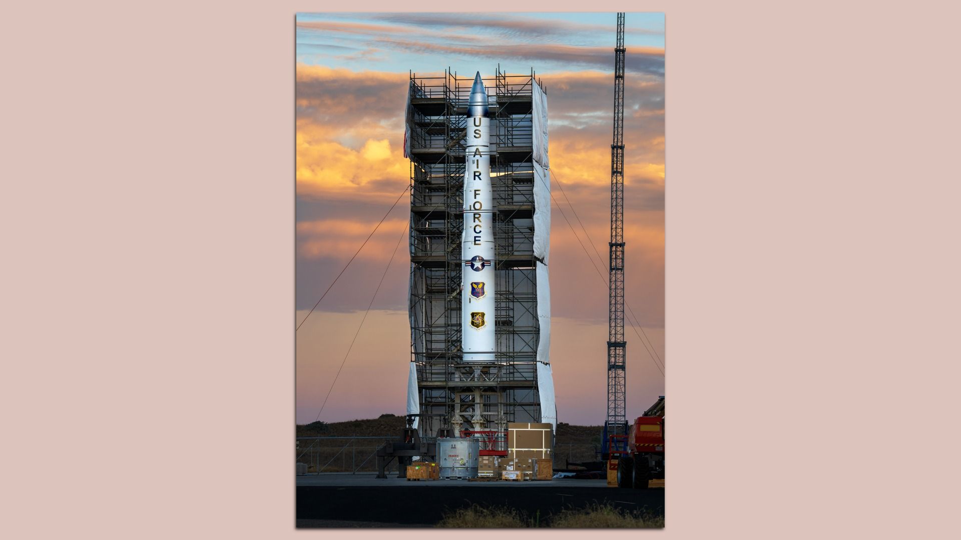 A large missile surrounded by scaffolding at sunset.