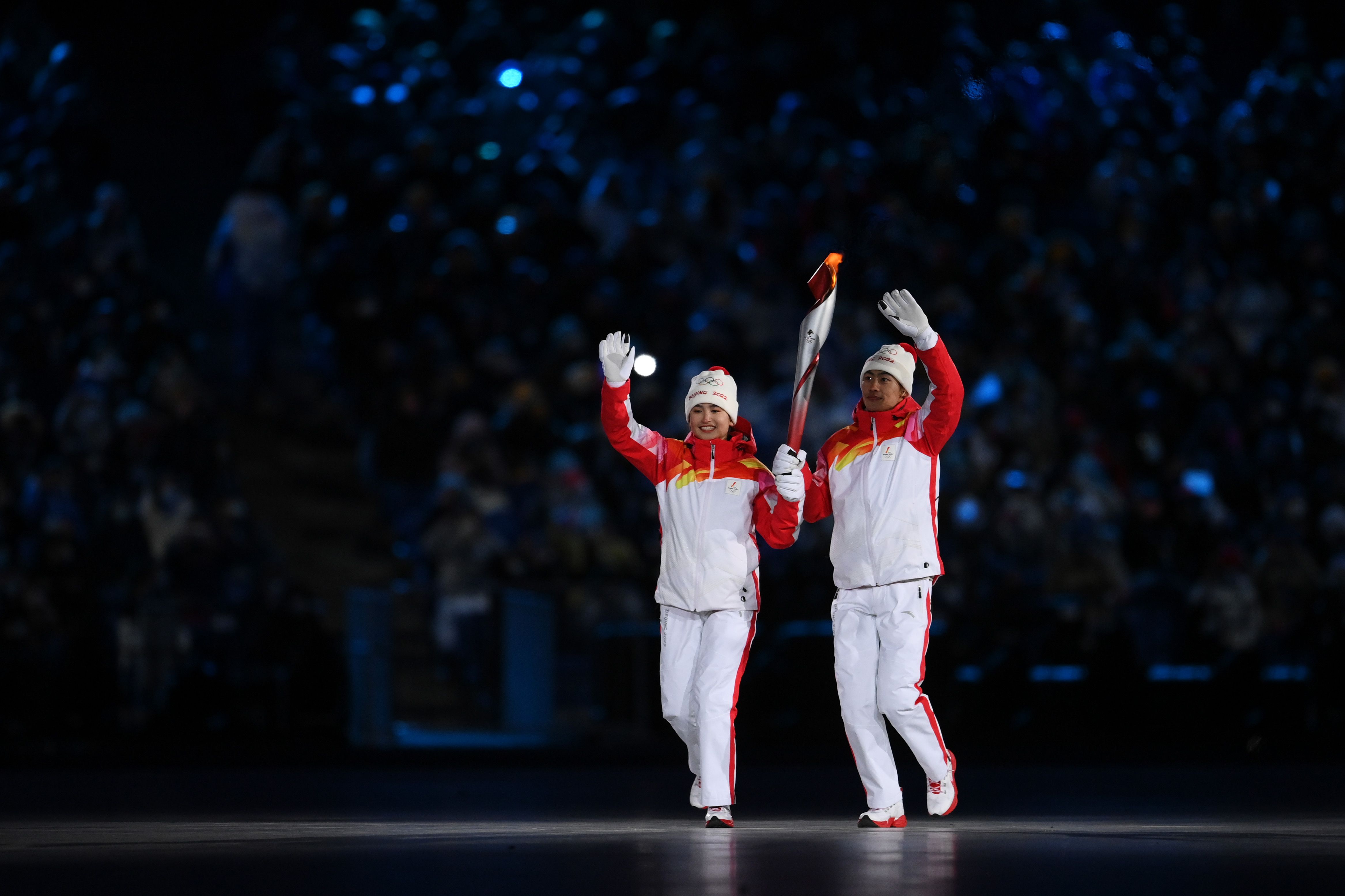 Torch bearers Dinigeer Yilamujiang and Jiawen Zhao of Team China hold the Olympic flame during the Opening Ceremony of the Beijing 2022 Winter Olympics.