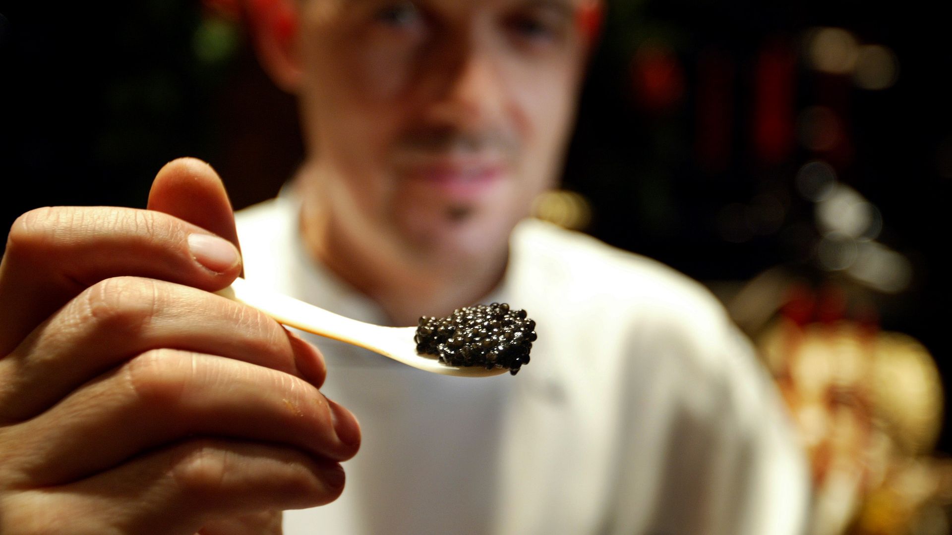 A man holds up caviar on a spoon.