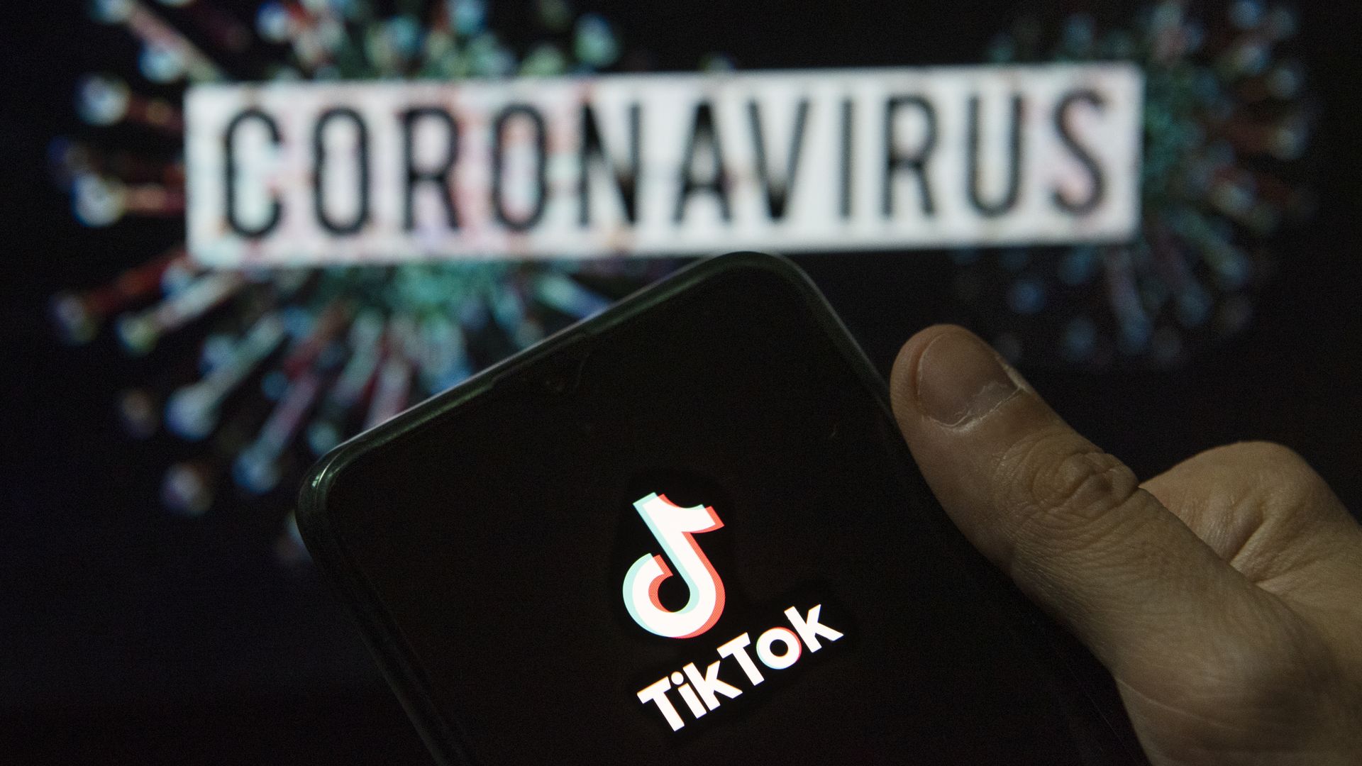 A photo illustration of the TikTok logo on a smartphone against a coronavirus backdrop.