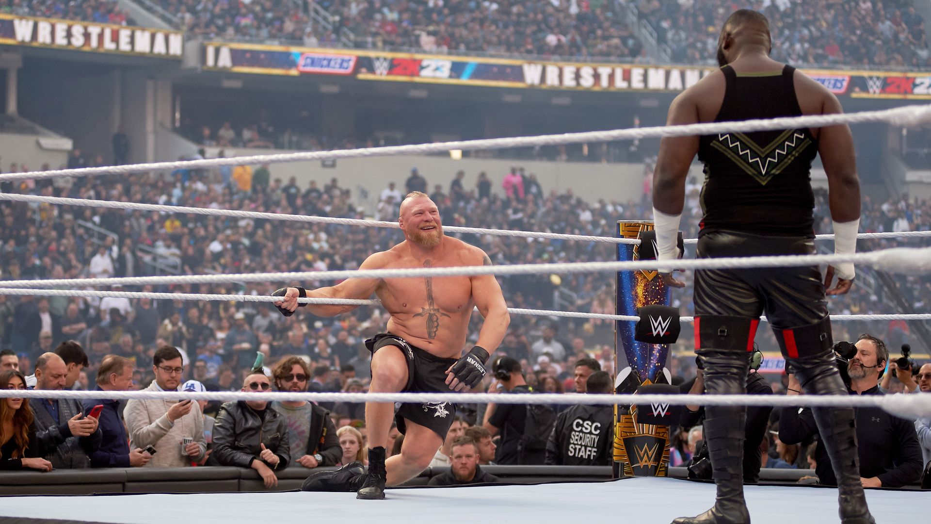 Brock Lesnar in the ring smiling, with fans in the background 