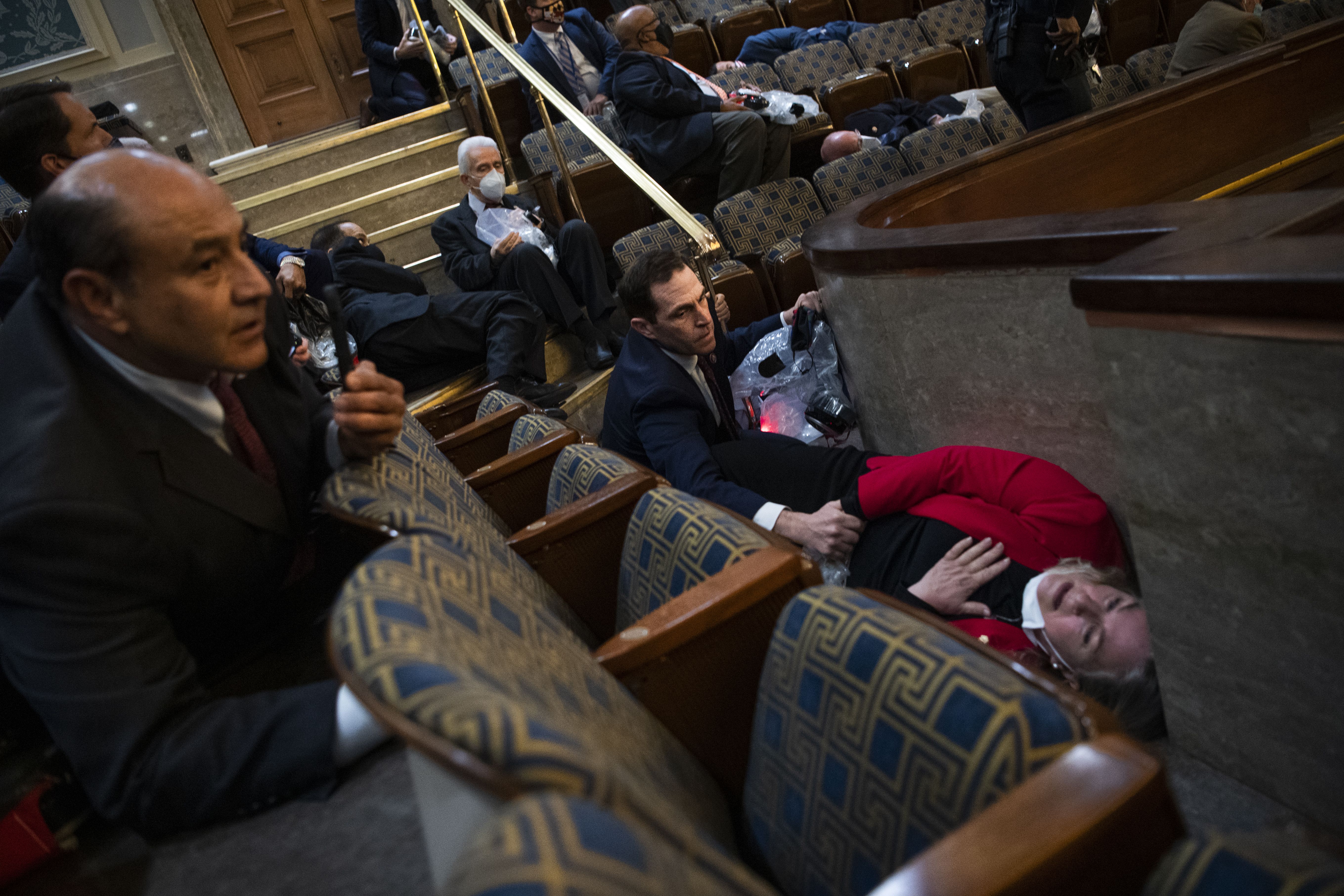 Photo of House members hiding behind and under chairs