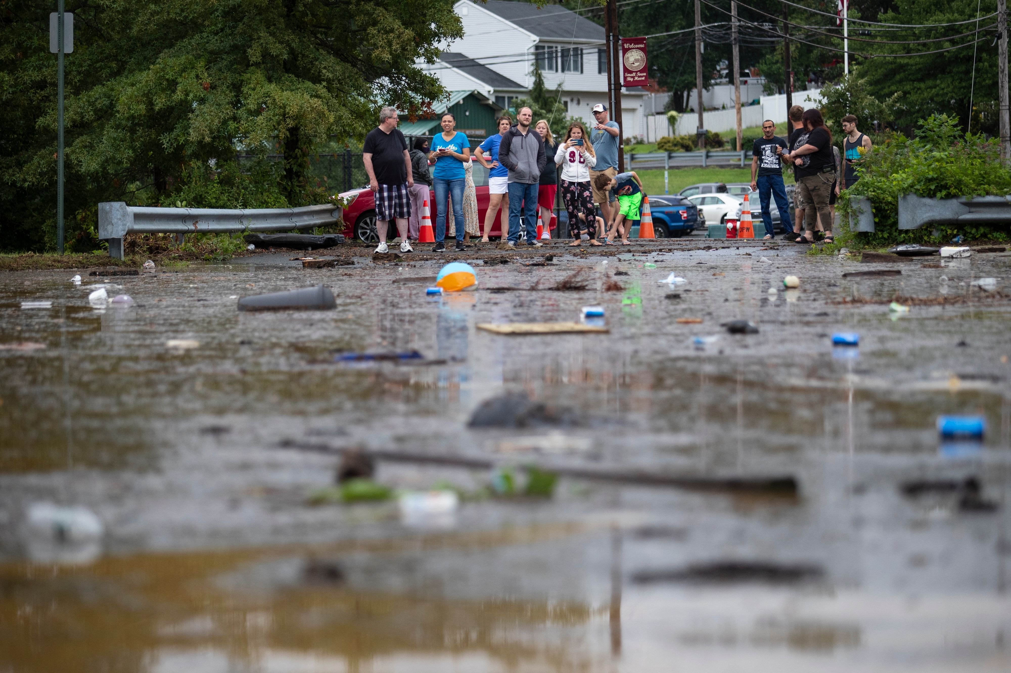 Evacuated residents look towards floating debris following a flash flood from Tropical Storm Henri