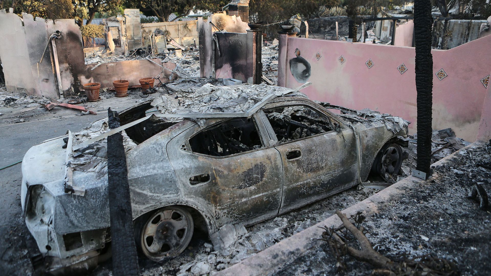 The remains of a destroyed car stand in front of a destroyed home in the aftermath of the Holiday Fire on July 7, 2018 in Goleta, California.