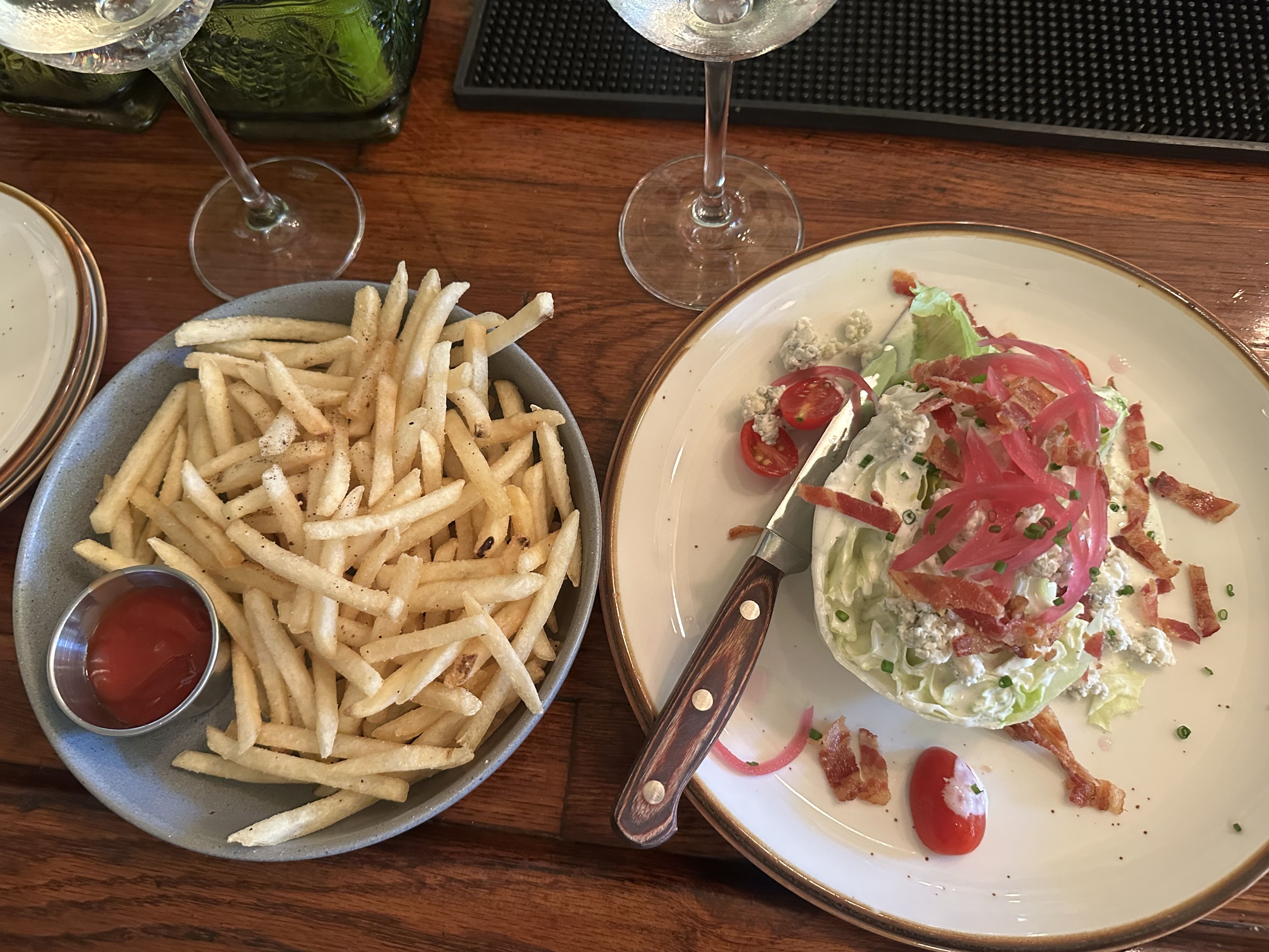 A Wedge salad next to a plate of fries 