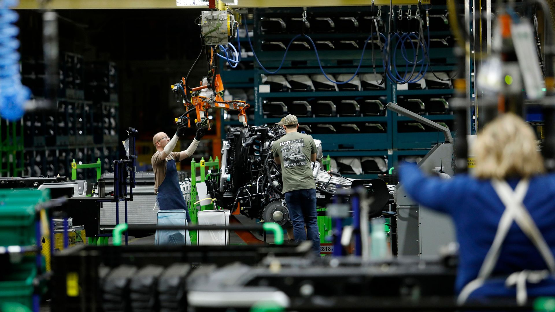 Line workers work on the chassis of full-size General Motors pickup trucks at the Flint Assembly plant 