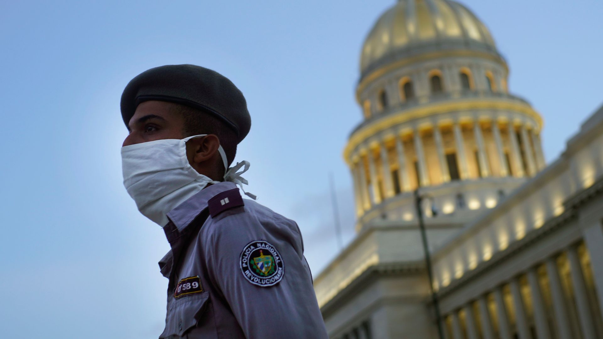 Photo of a masked police officer with the Cuba Capitol in the background