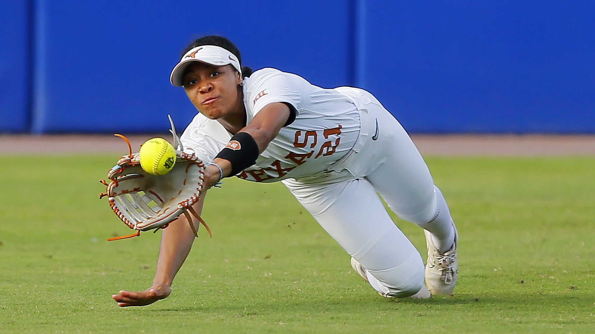 A softball player dives for a ball.