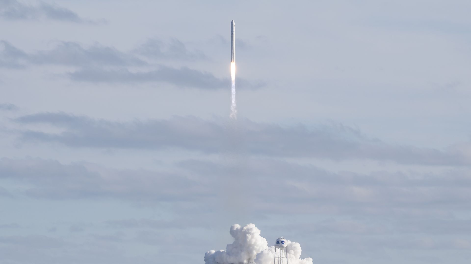 In this image, a rocket flies above a white cloud of exhaust 