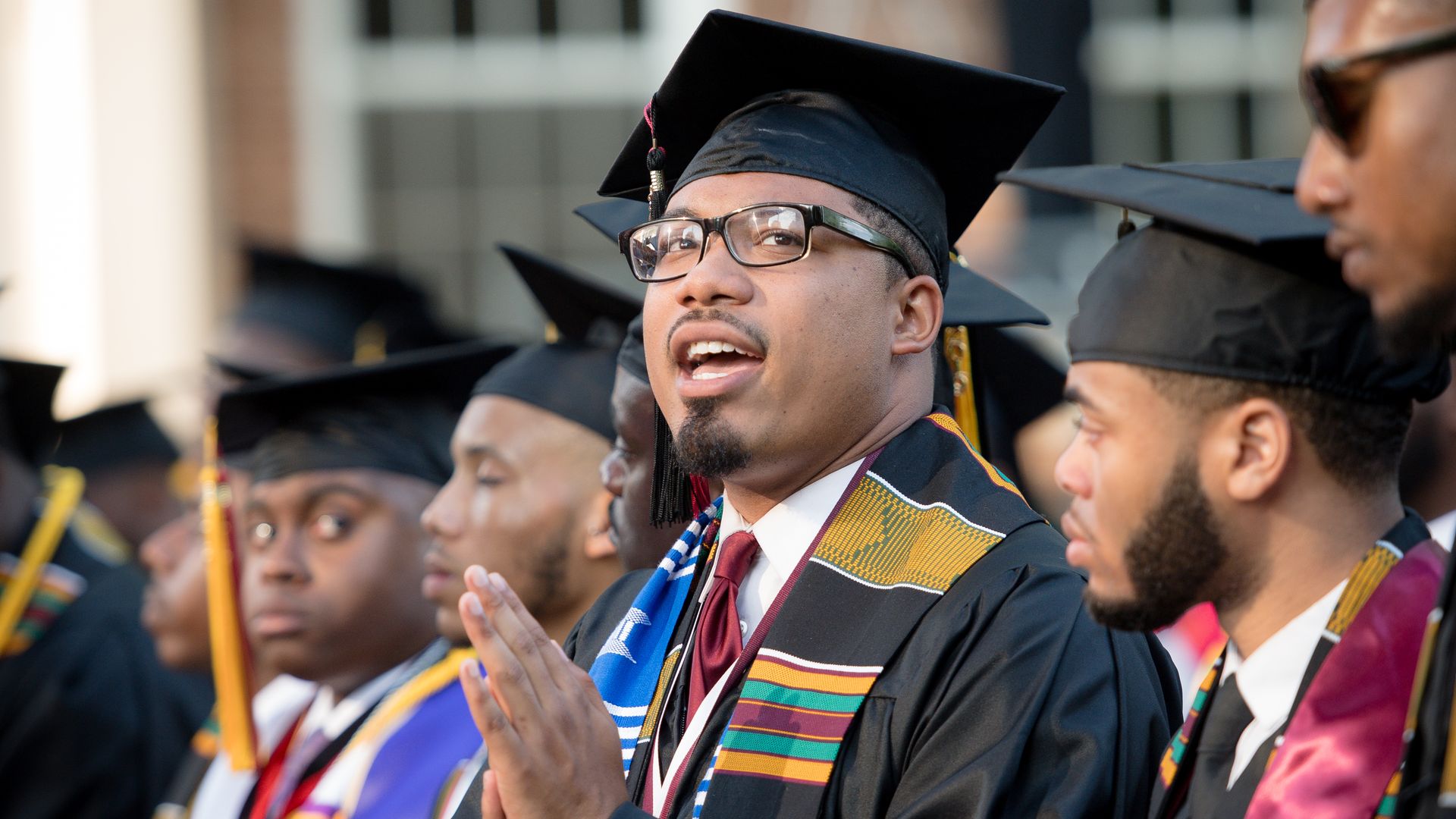 Photo of men wearing graduations caps and gowns