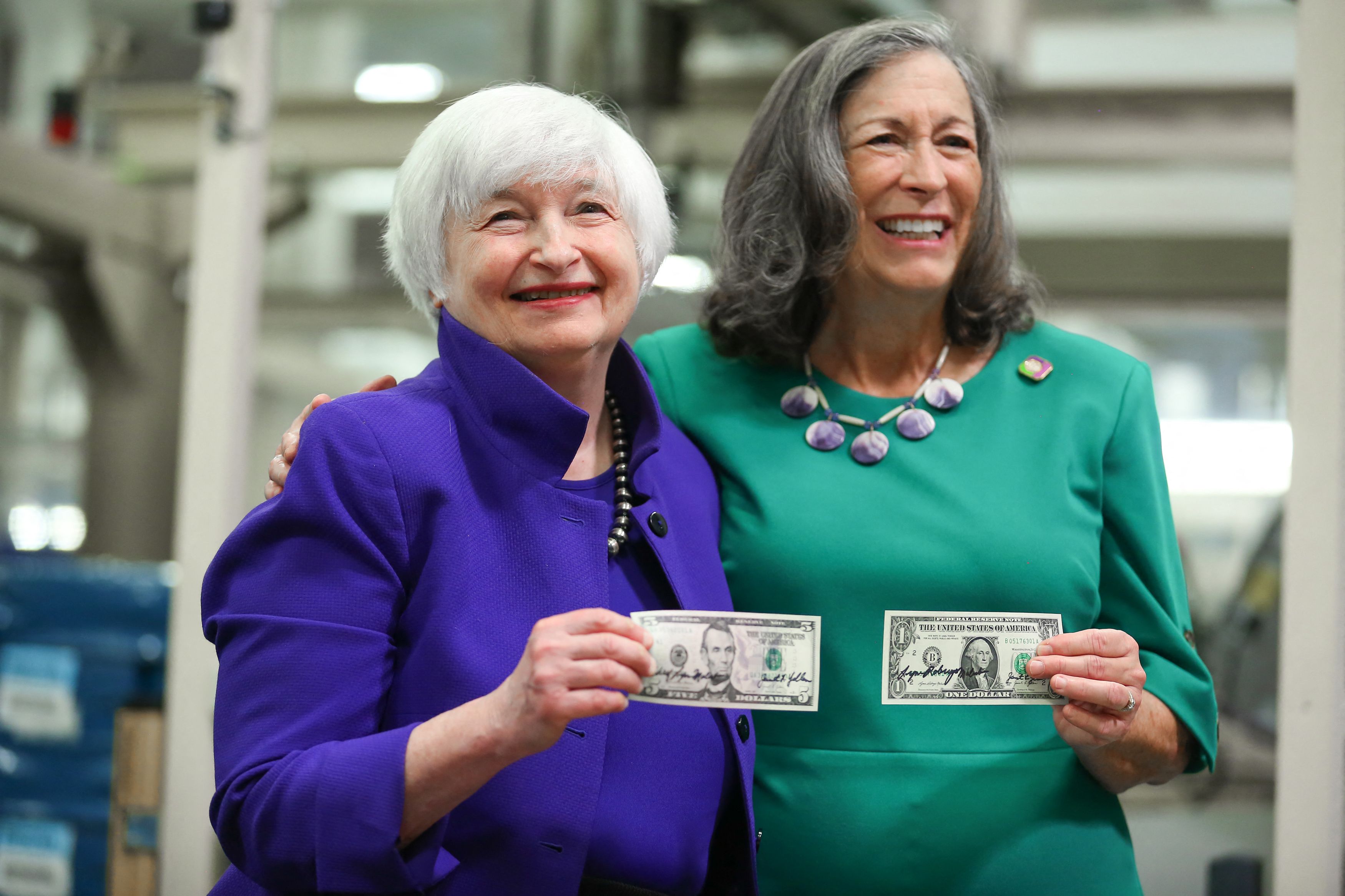 Janet Yellen and Marilynn Malerba hold U.S. currency notes with their signatures at a printing facility in Fort Worth.